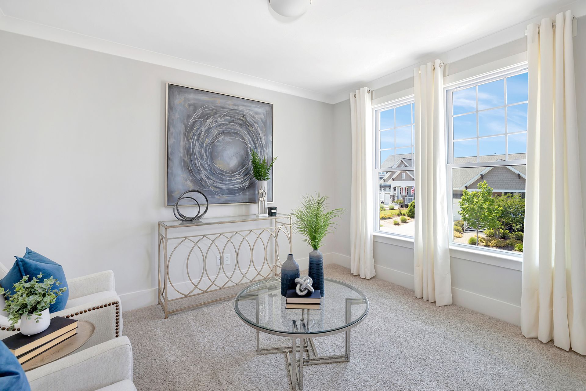 A living room with a glass coffee table and two chairs.