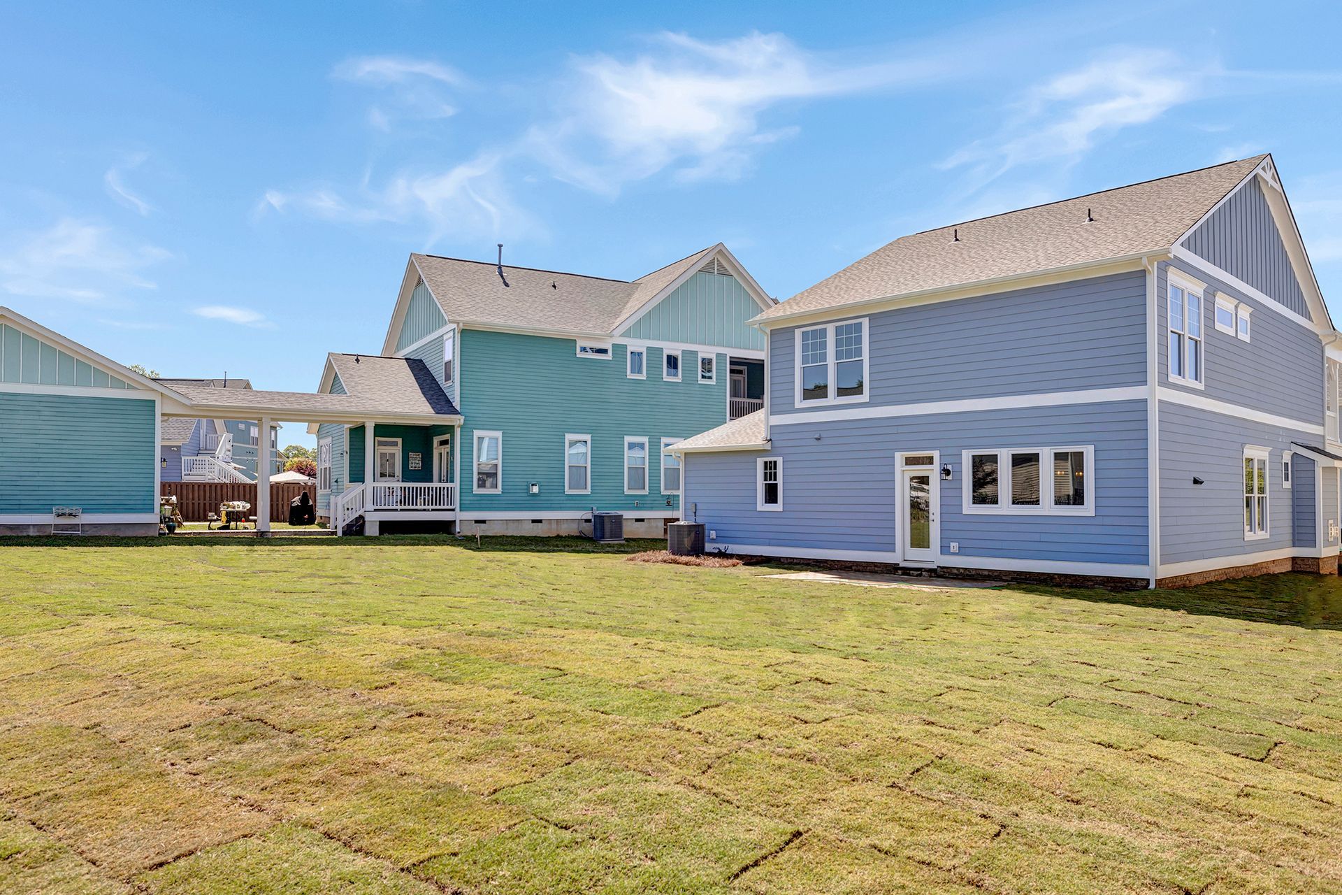 A couple of houses sitting next to each other on top of a lush green field.