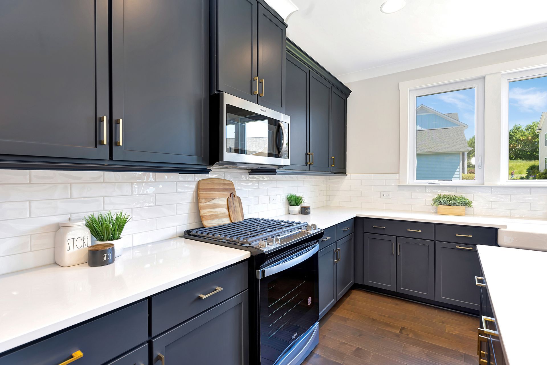 A kitchen with black cabinets , stainless steel appliances , and white counter tops.