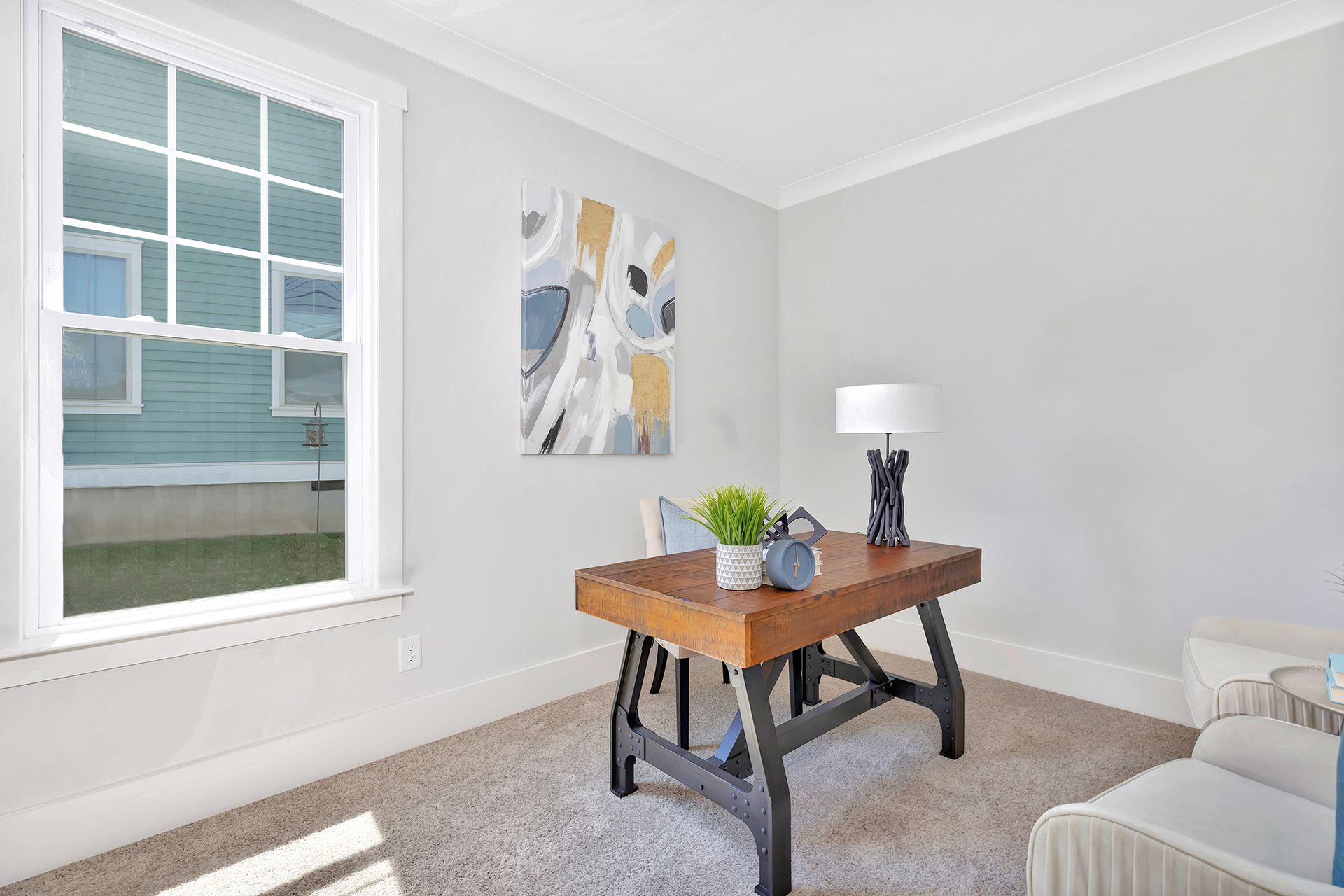 A living room with a desk , chair , lamp and window.