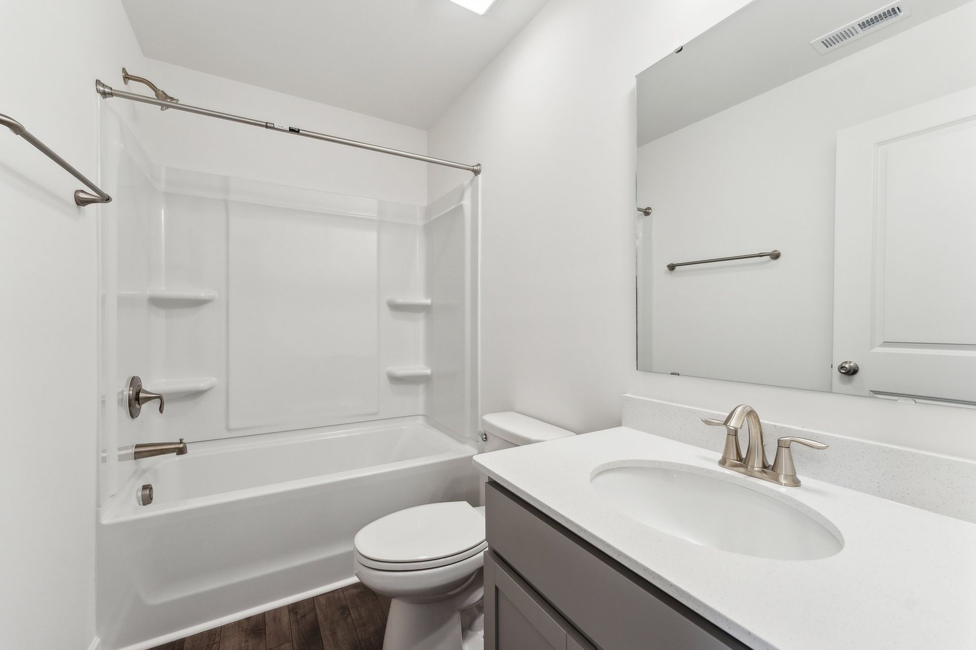 A bathroom with a toilet , sink , bathtub and mirror.