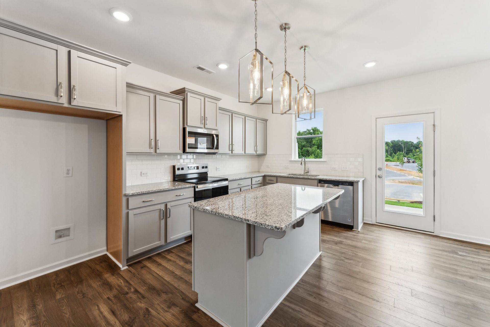 A kitchen with white cabinets , granite counter tops , stainless steel appliances , and hardwood floors.