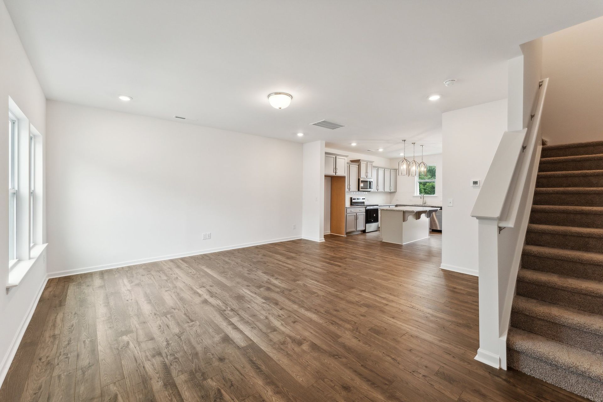 An empty living room with hardwood floors and stairs in a house.