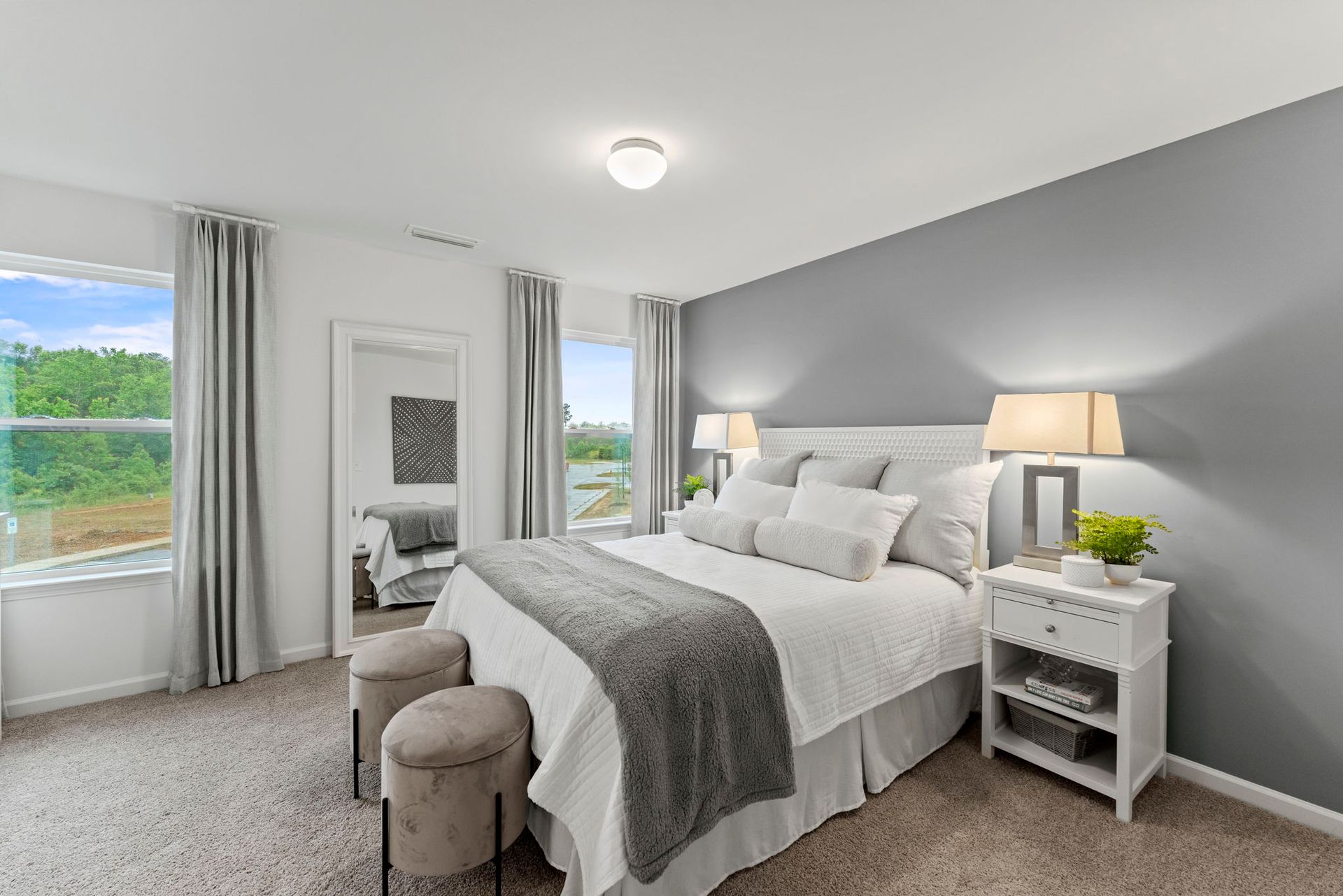 A bedroom with a large bed , nightstands , lamps and a window.