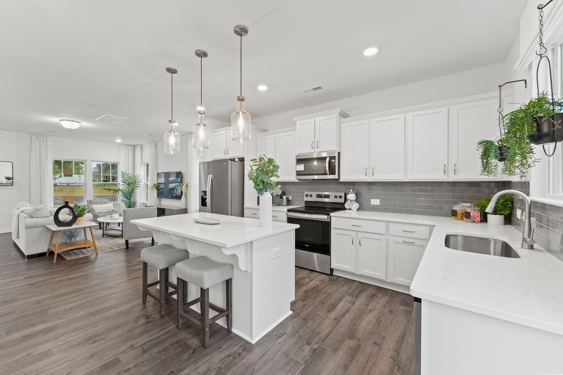 A kitchen with white cabinets , stainless steel appliances , and a large island.
