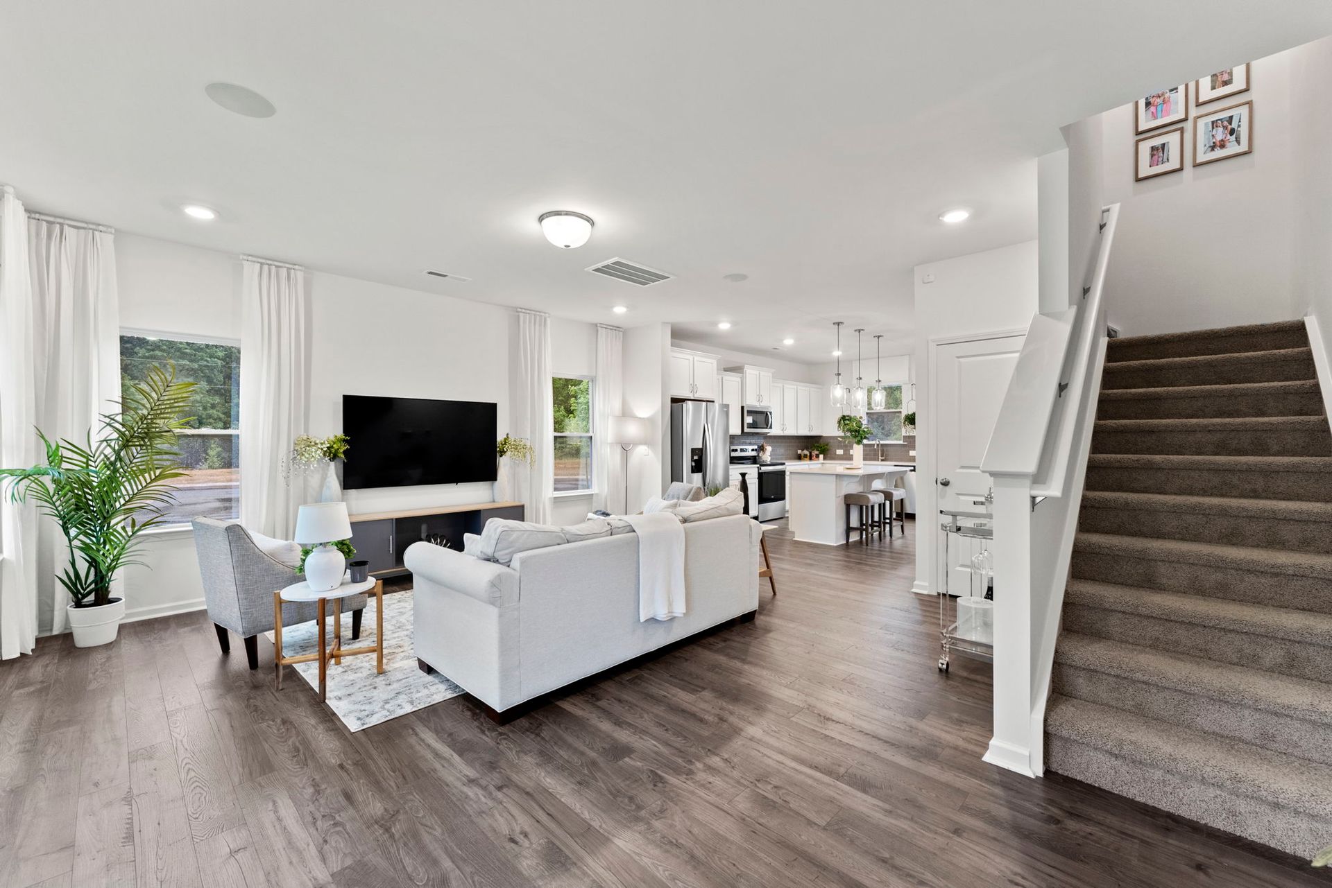 A living room with a couch , chairs , stairs and a television.