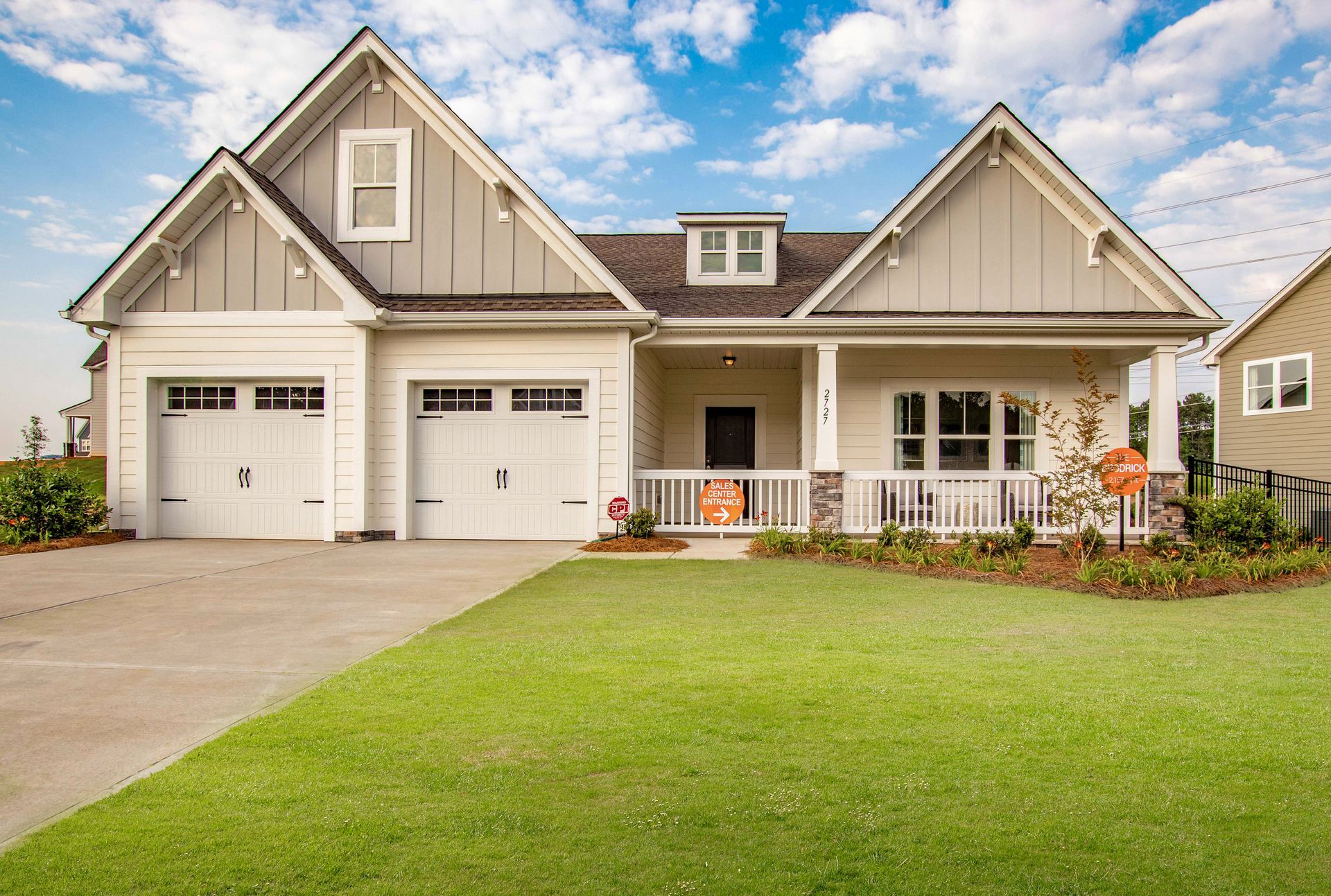 a large white house with a porch and two garages .