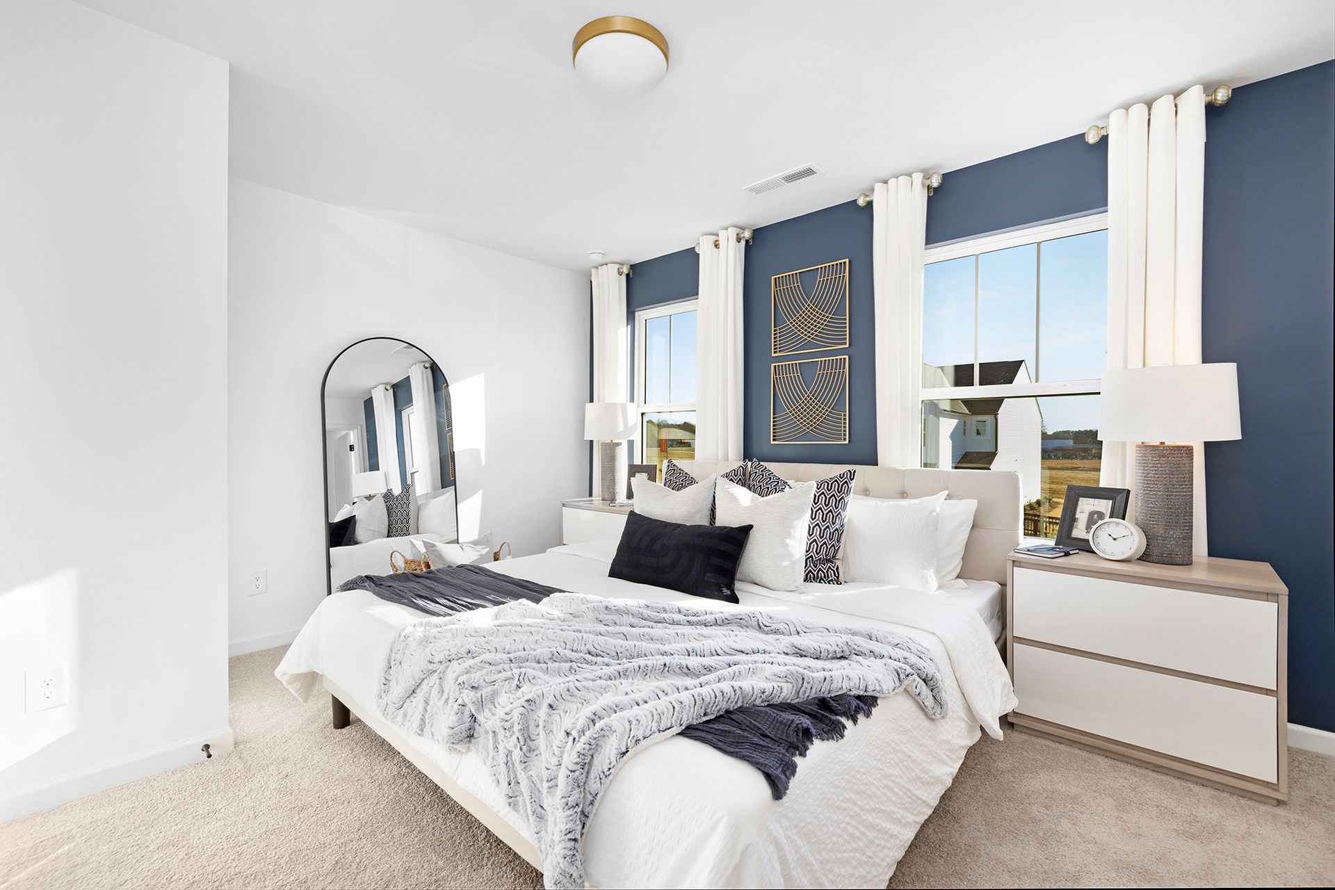 A bedroom with a bed , nightstand , mirror and blue walls.