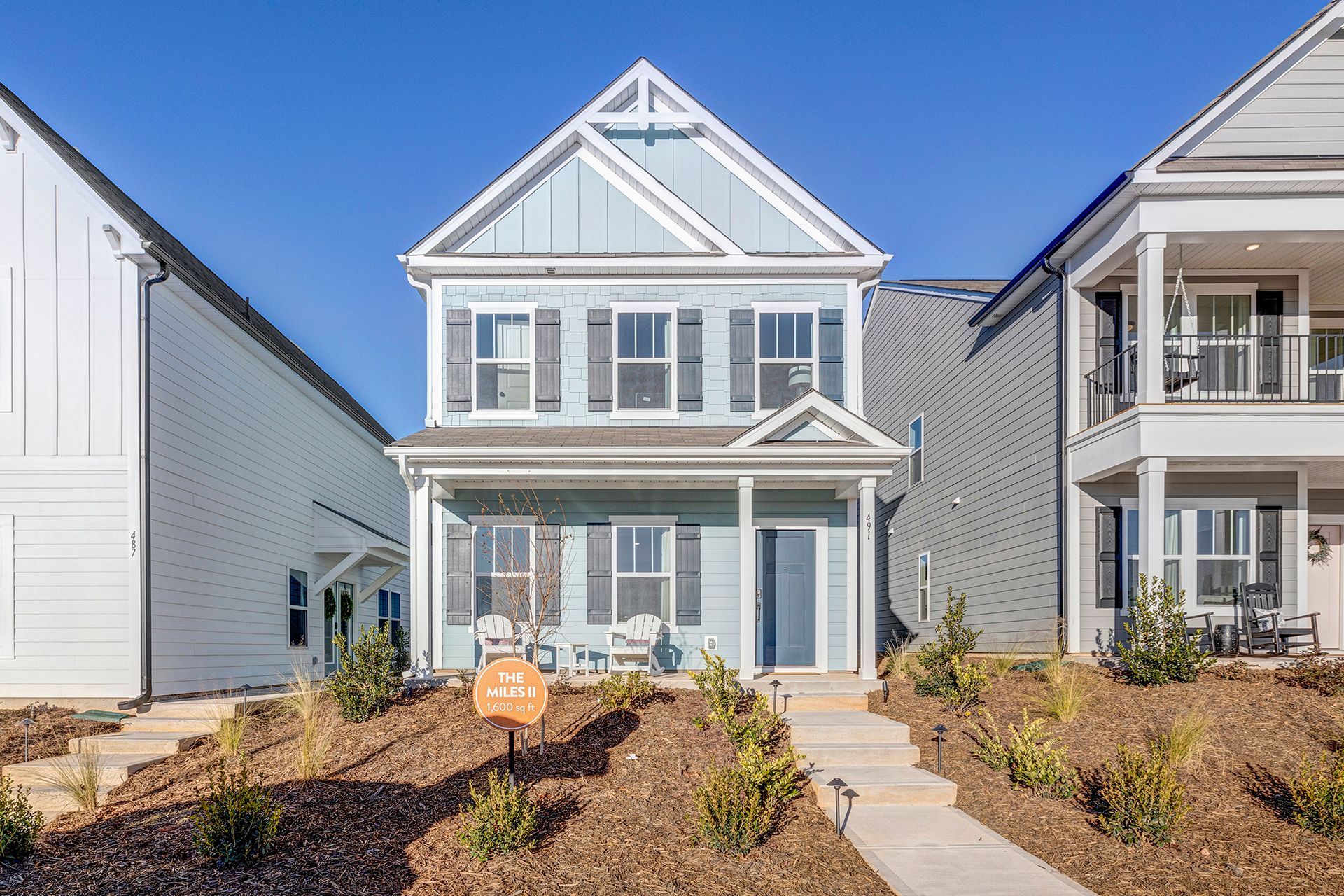 A blue and white house with a sign in front of it is for sale.
