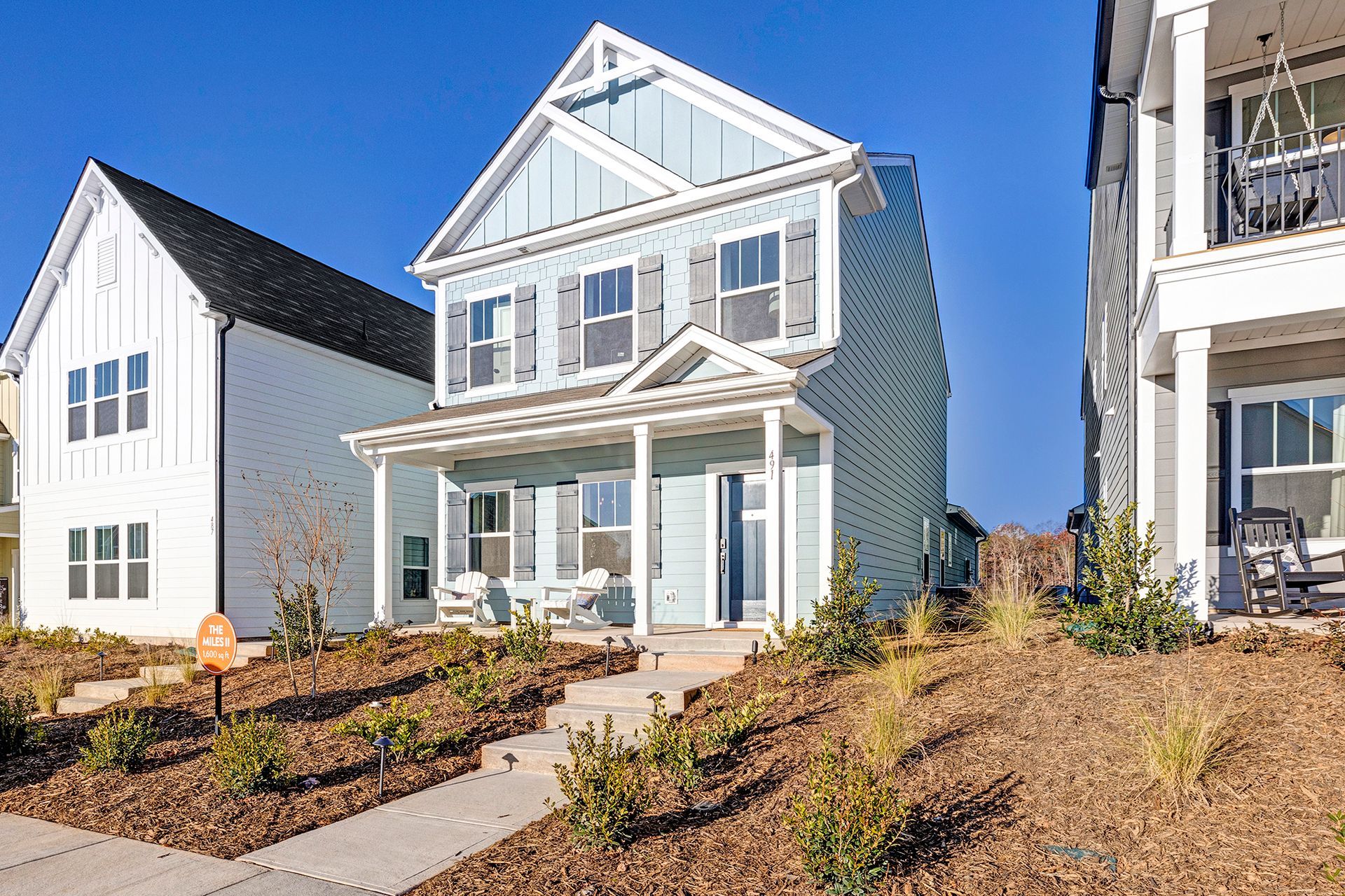 A blue and white house with a sign in front of it is for sale.