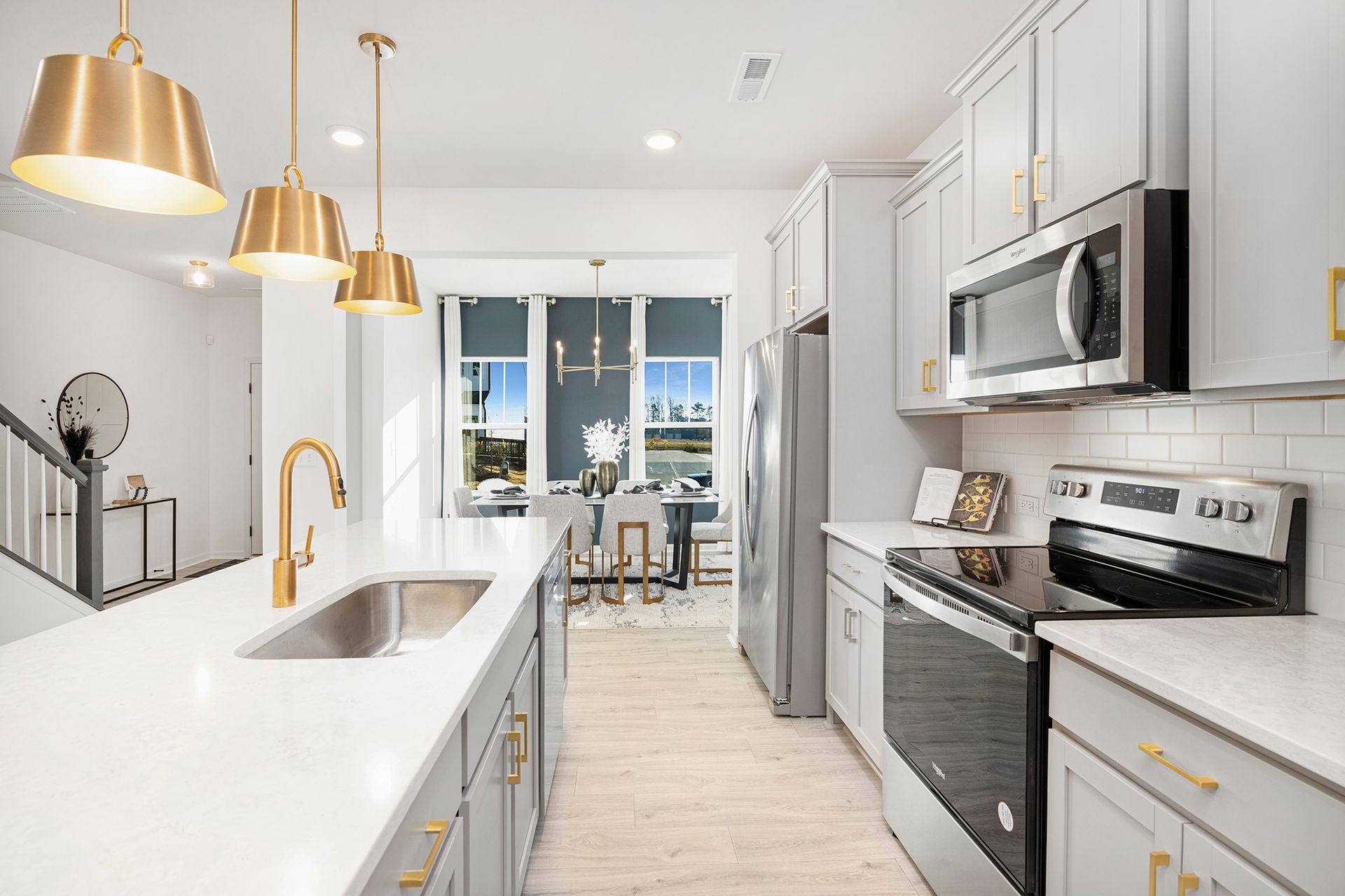 A kitchen with white cabinets , stainless steel appliances , a sink , and a microwave.