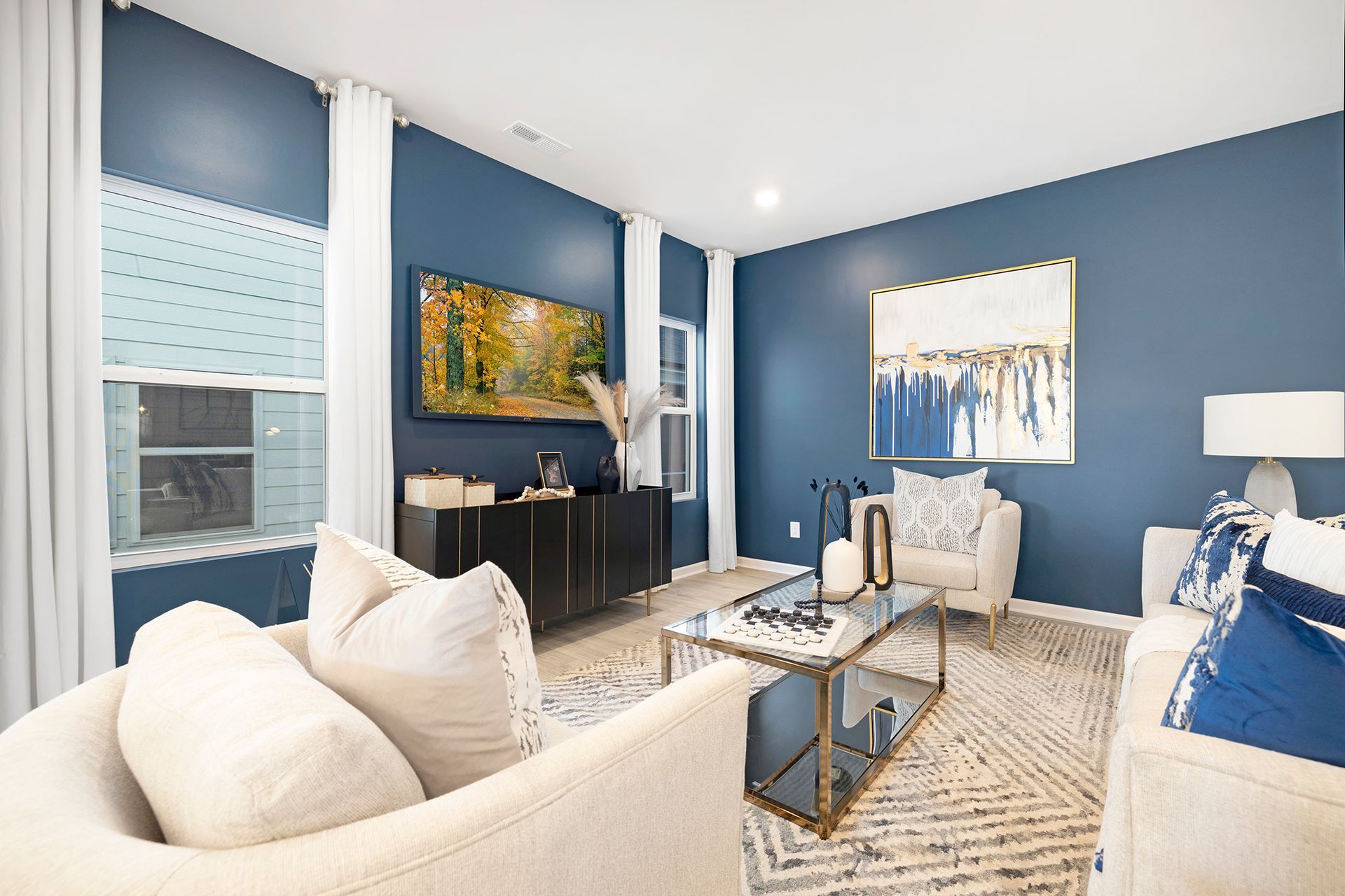 A living room with blue walls , white furniture , a coffee table and a television.