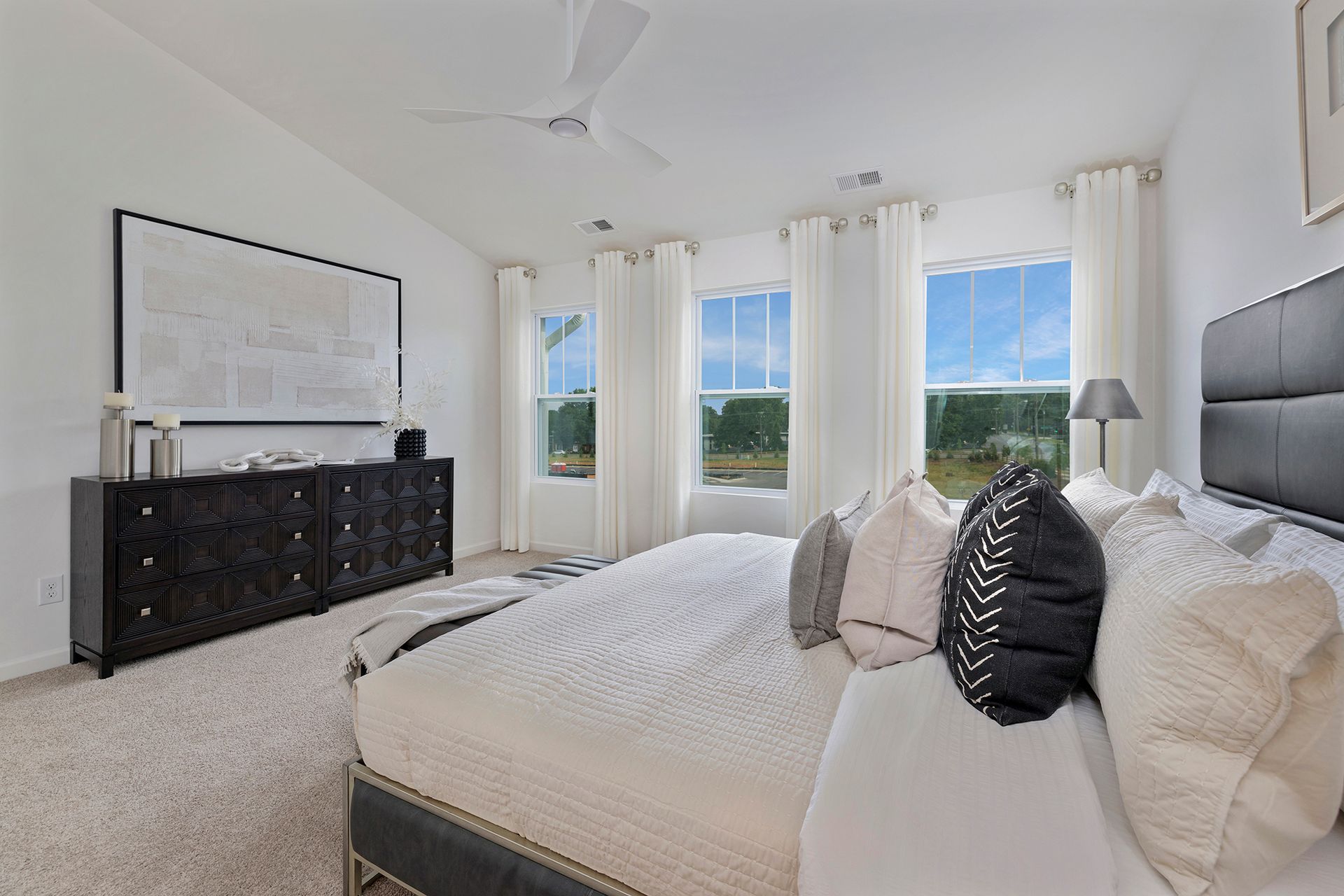 A bedroom with a bed , dresser , and ceiling fan.