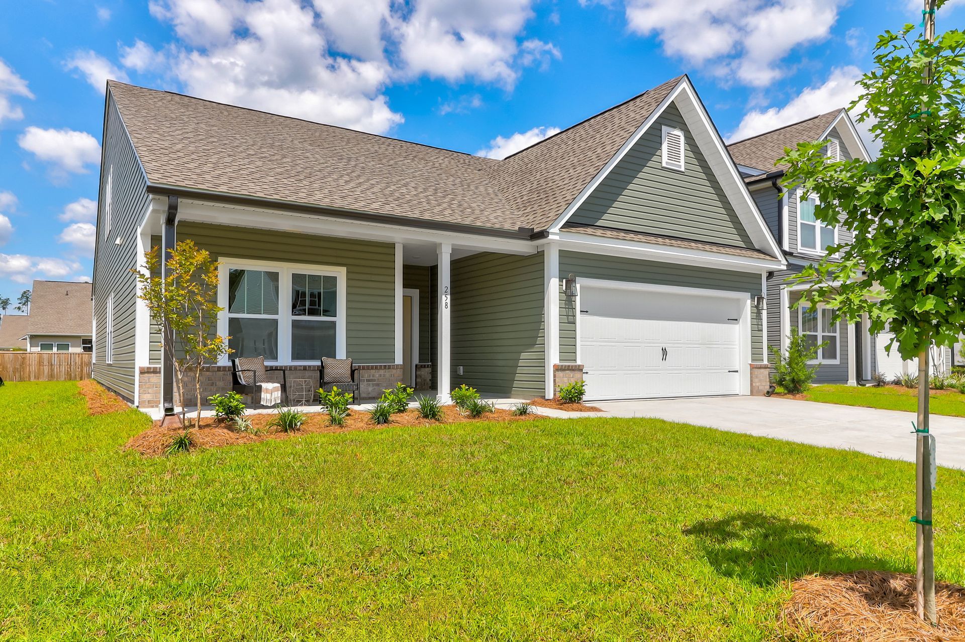A large house with a white garage door is sitting on top of a lush green lawn.