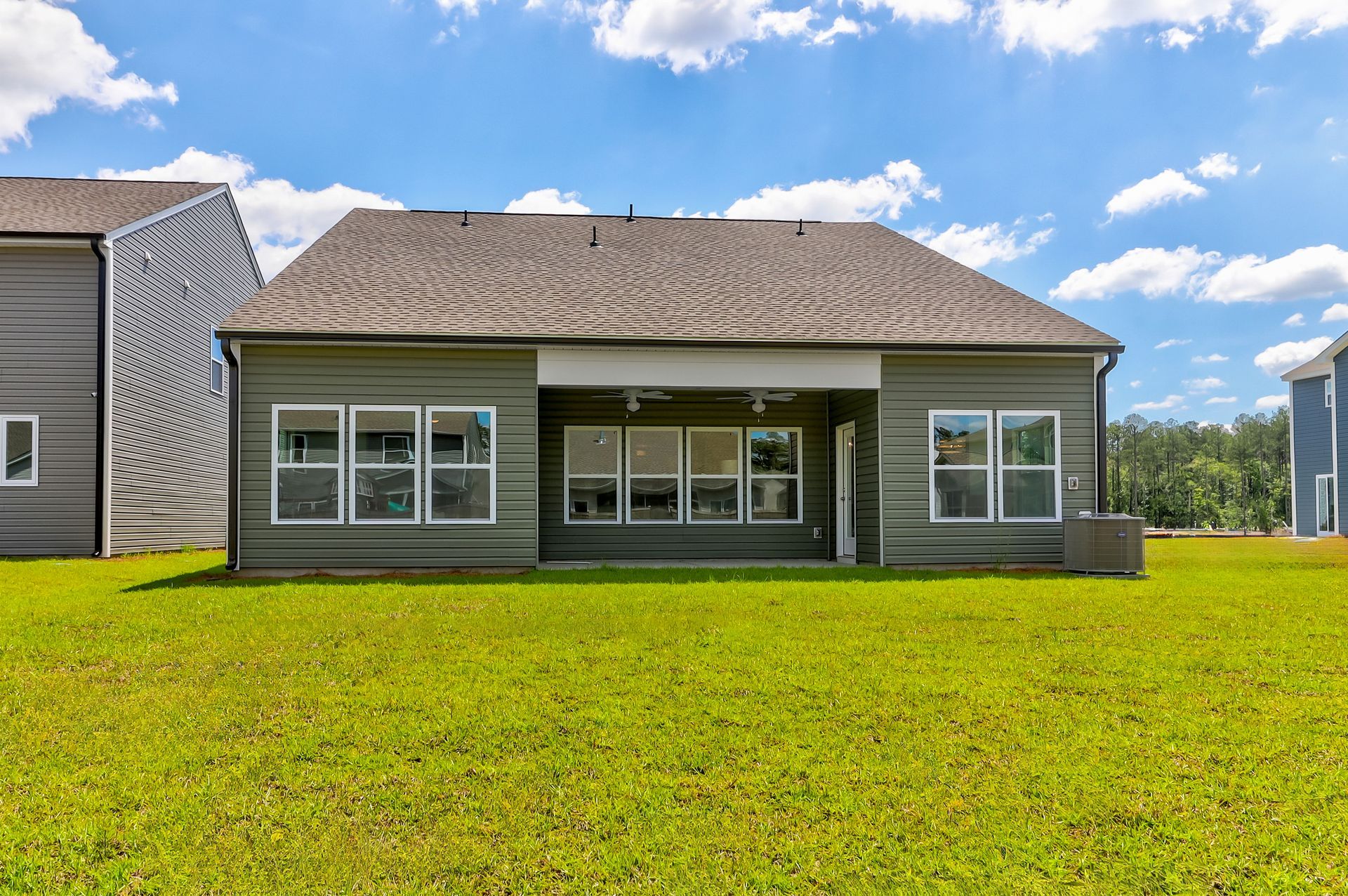 The back of a house with a large lawn in front of it.