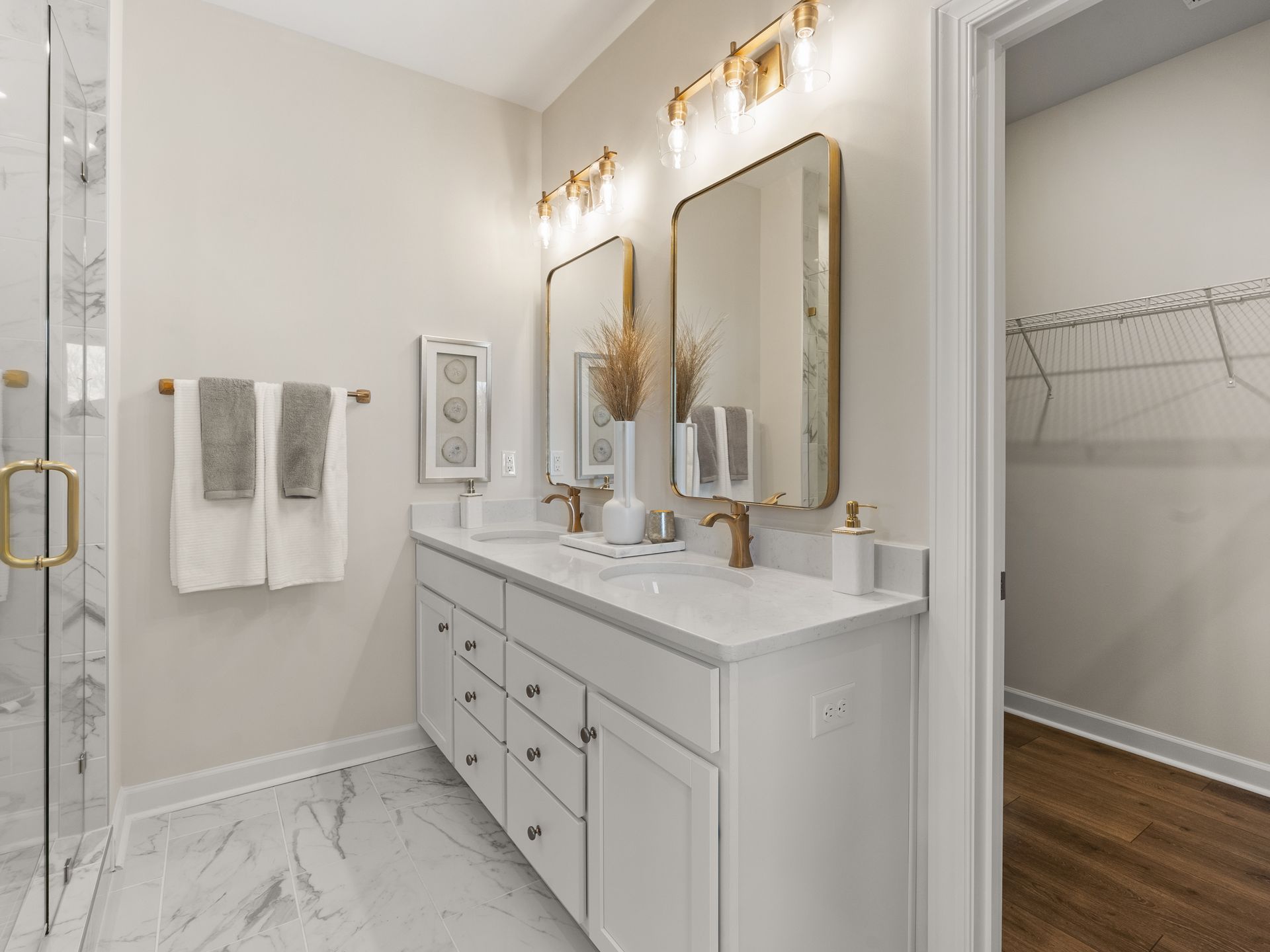 A bathroom with two sinks , two mirrors and a walk in shower.