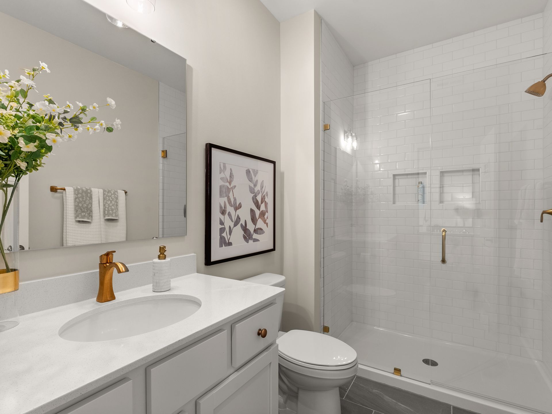 A bathroom with a sink , toilet , shower and mirror.