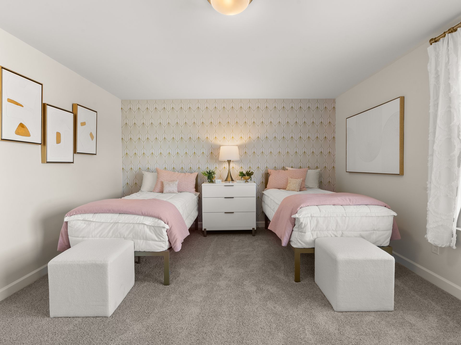 A bedroom with two beds and two ottomans.