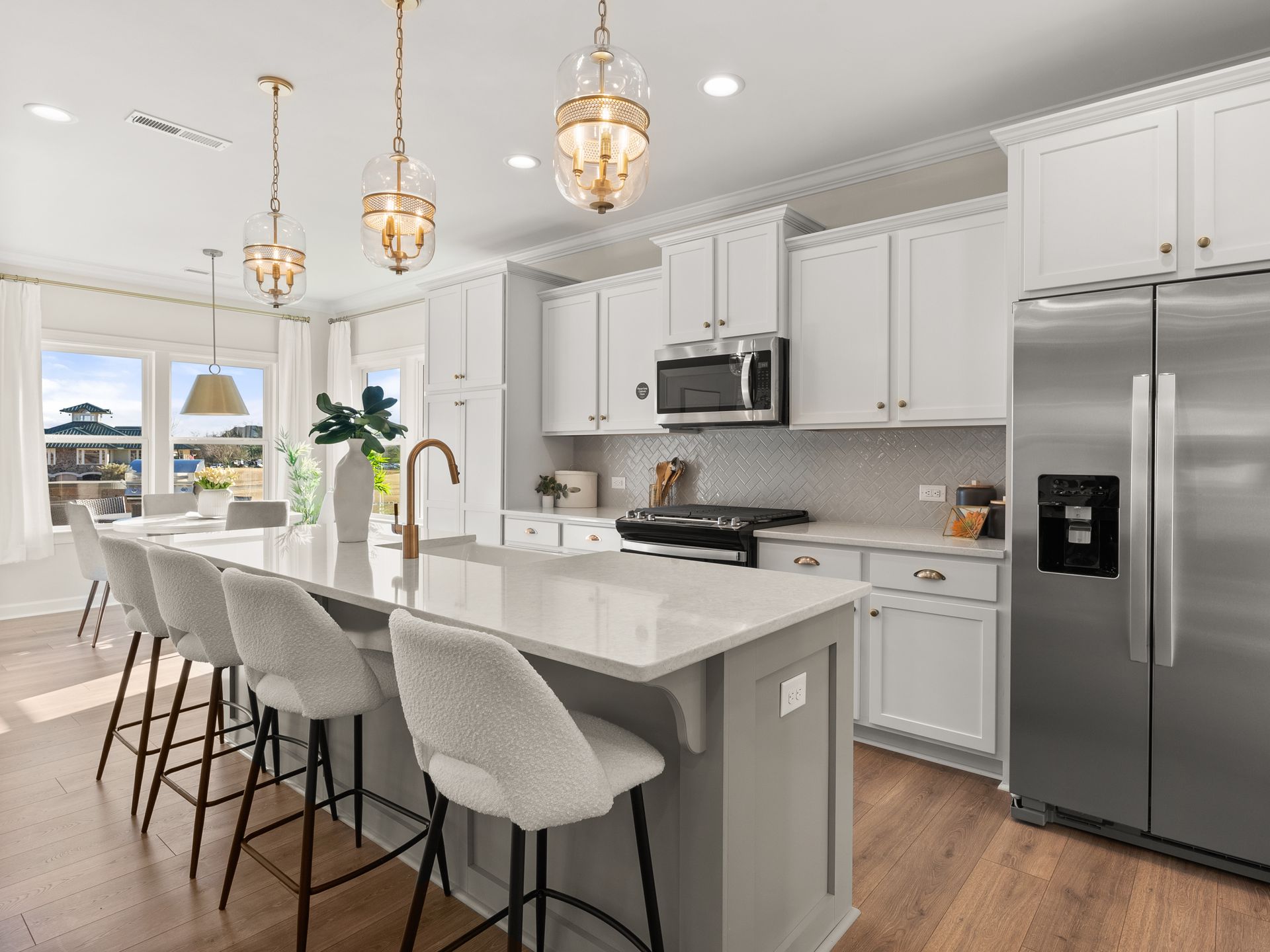 A kitchen with white cabinets , stainless steel appliances , and a large island.