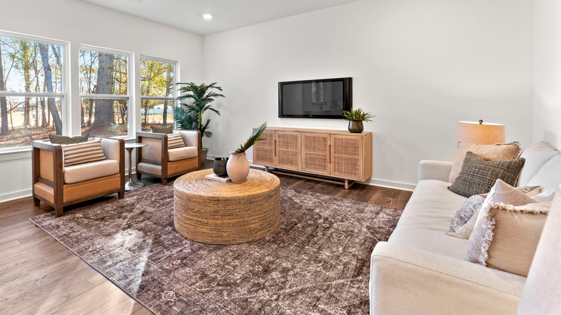 a living room with a couch , chairs , coffee table and television .