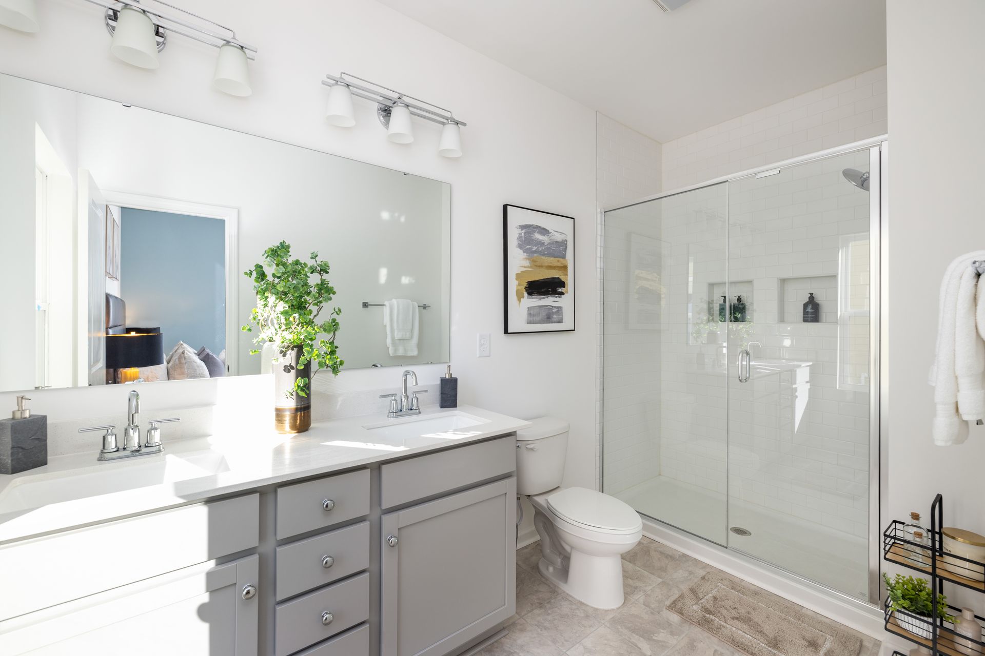 A bathroom with two sinks , a toilet , and a walk in shower.