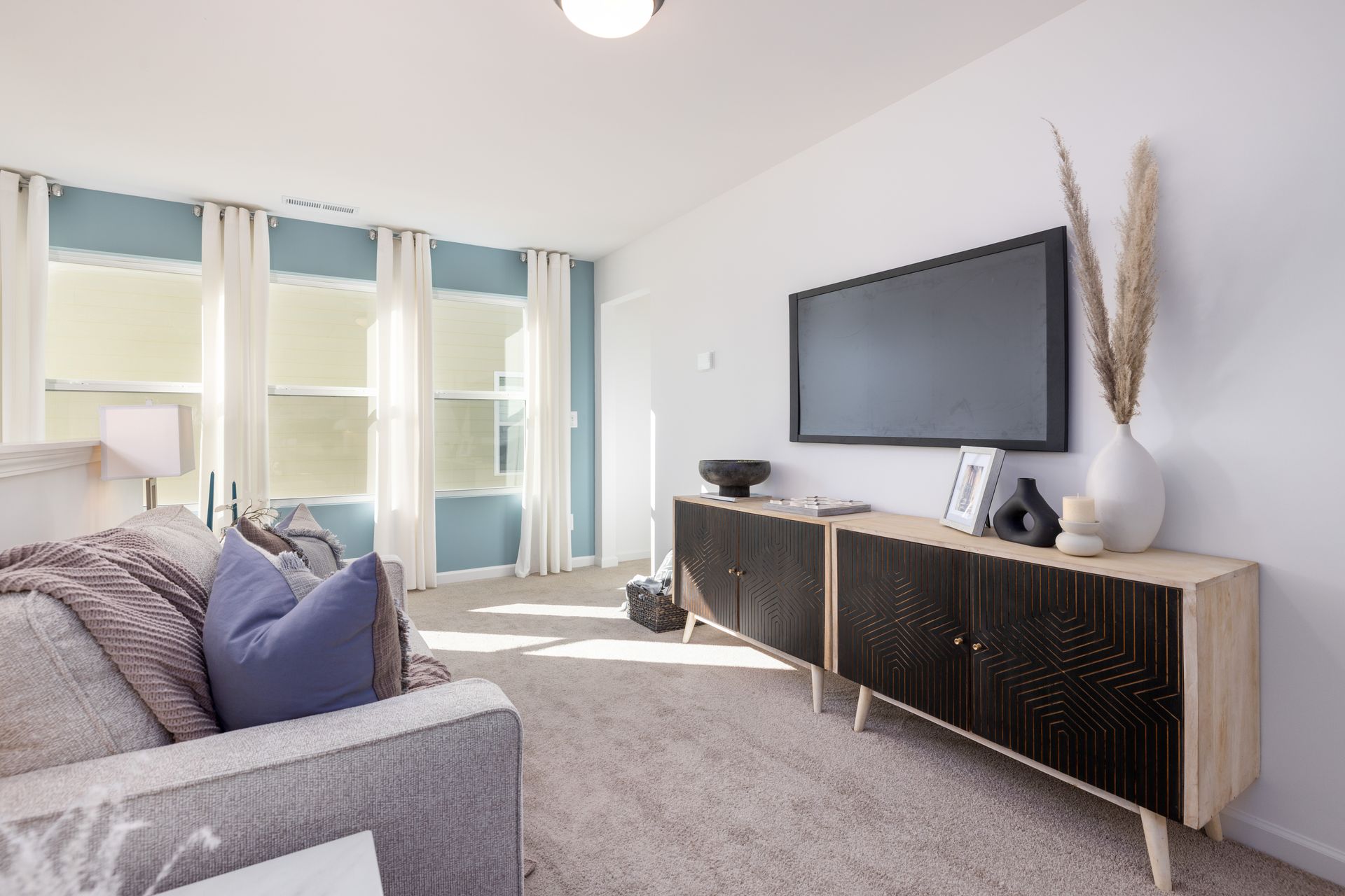 A living room with a couch and a flat screen tv on the wall.