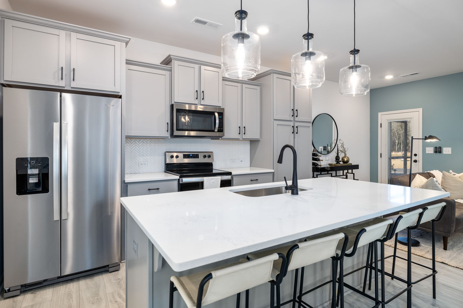 A kitchen with stainless steel appliances , white cabinets , a large island , and a refrigerator.