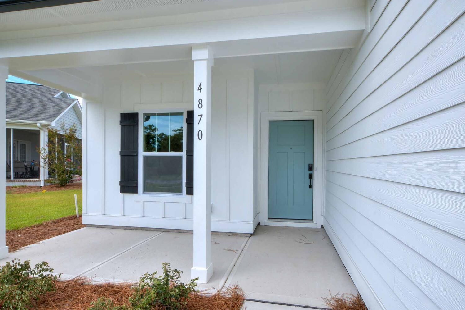 A white house with a blue door and a porch.