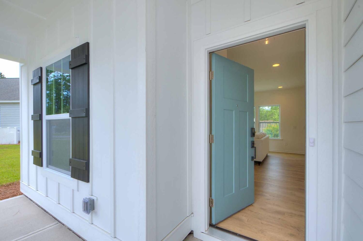 The front door of a white house with a blue door and a window.