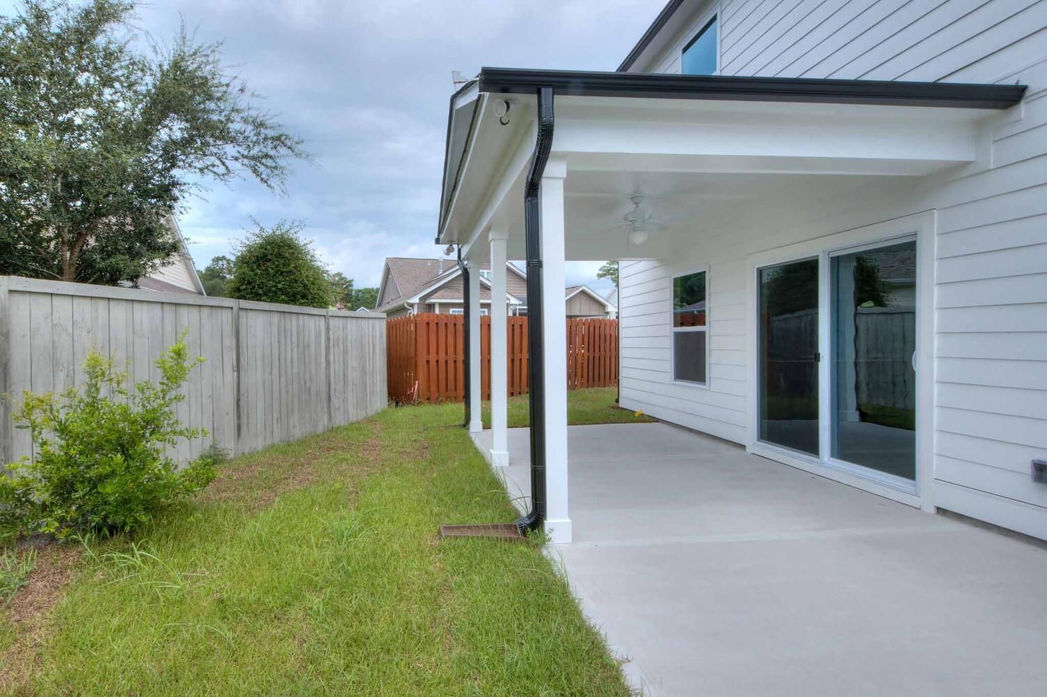 The backyard of a house with a covered patio and a wooden fence.