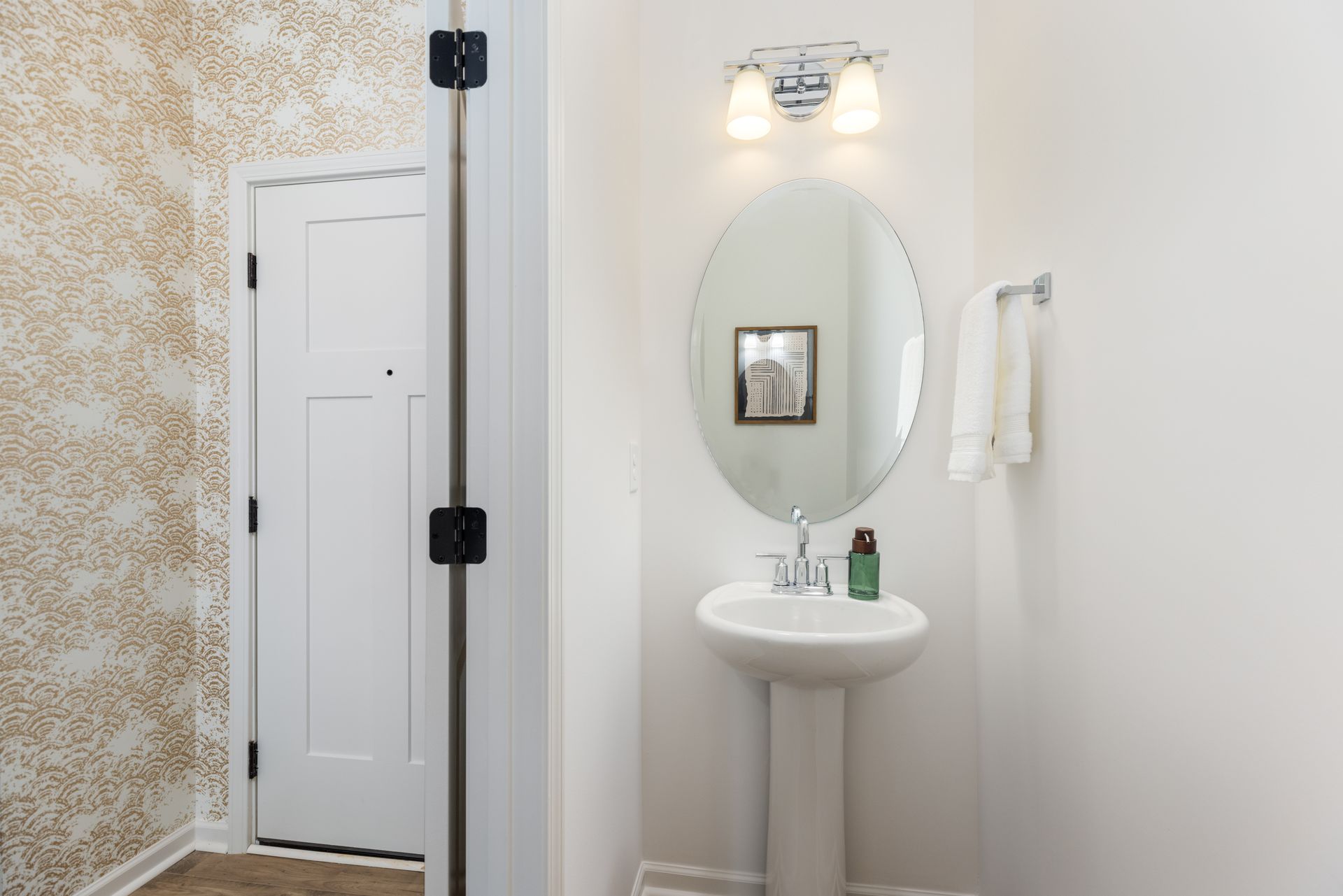 A bathroom with a sink , mirror and door.