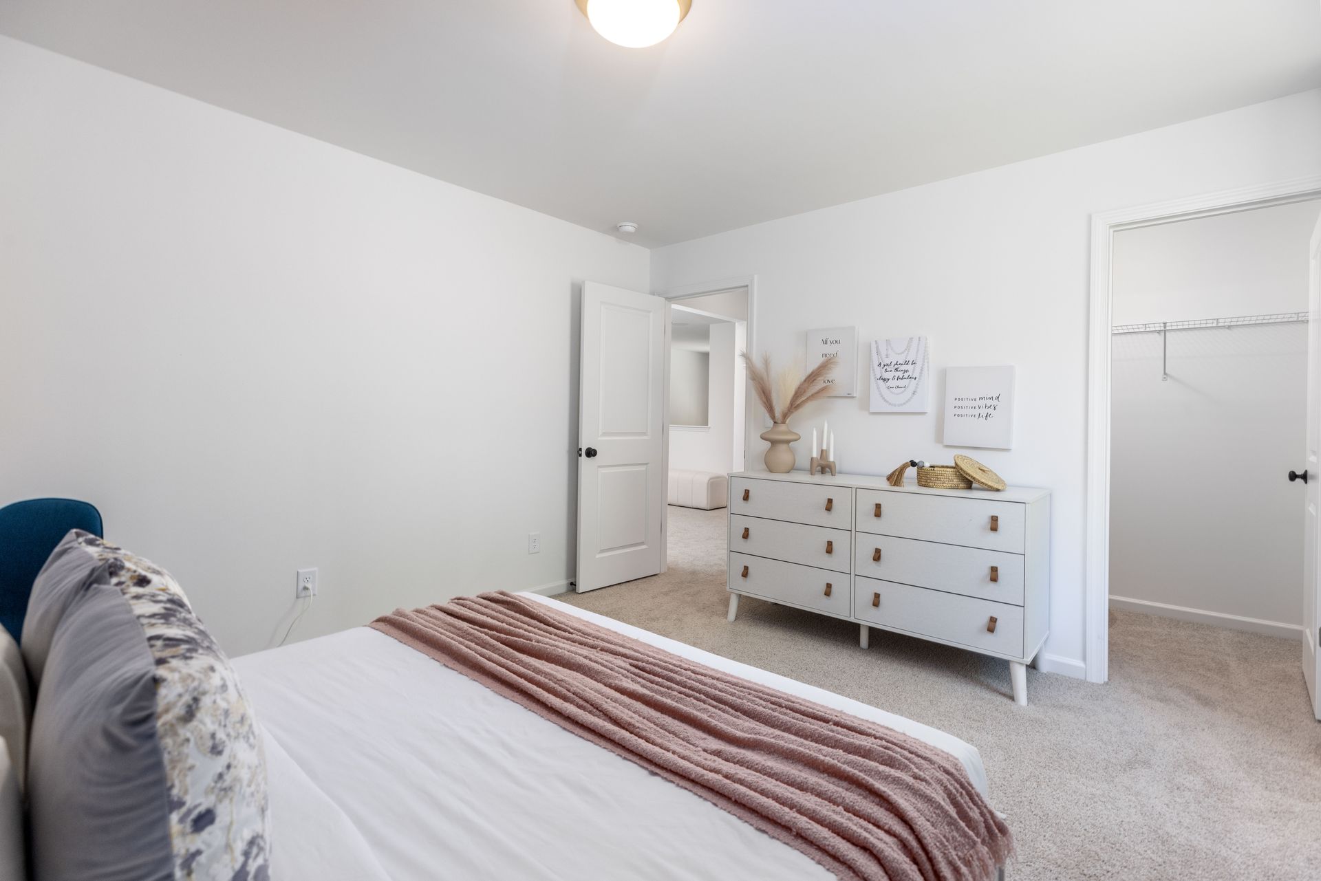 A bedroom with a bed , dresser , and walk in closet.