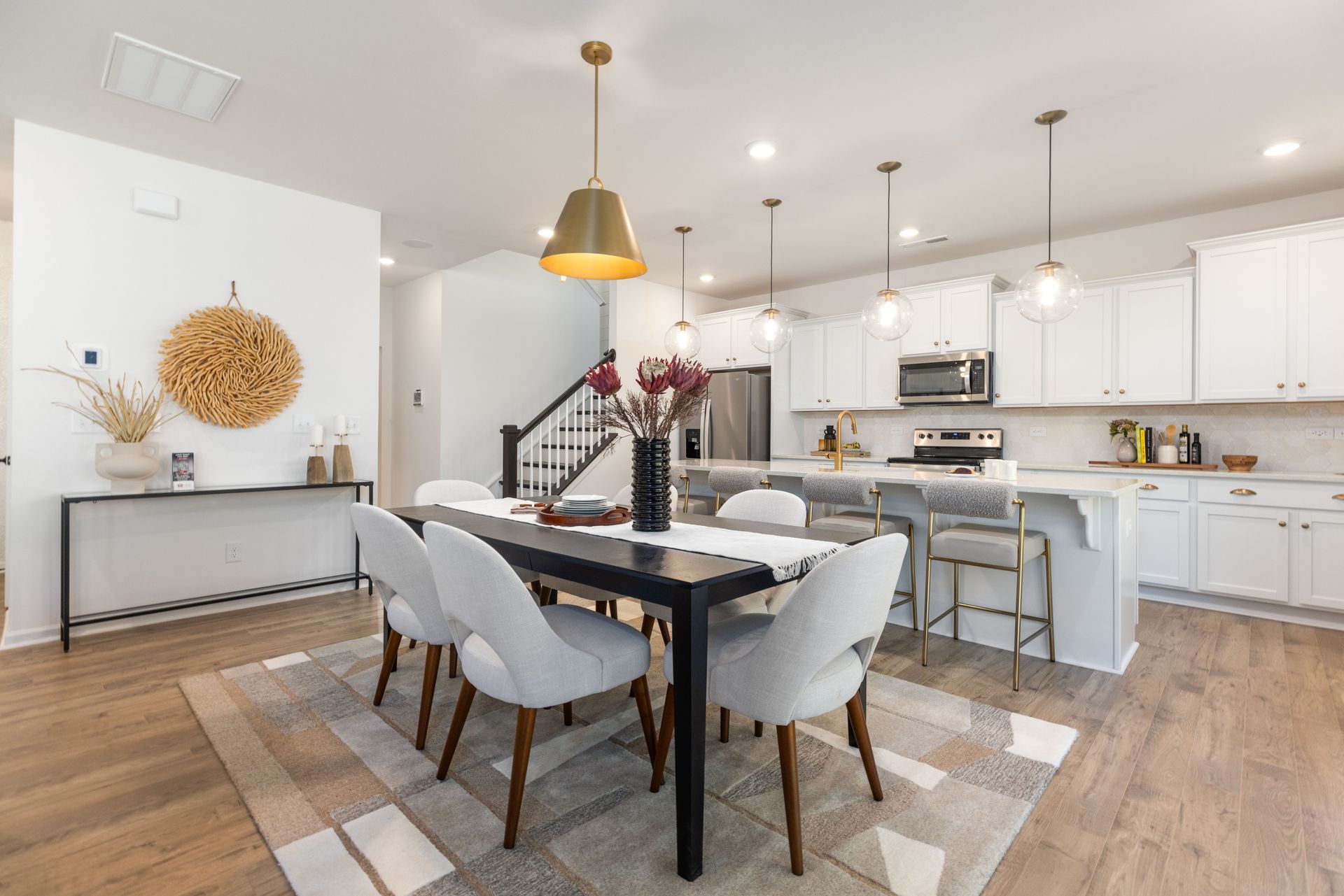 A dining room table and chairs in a kitchen with white cabinets.