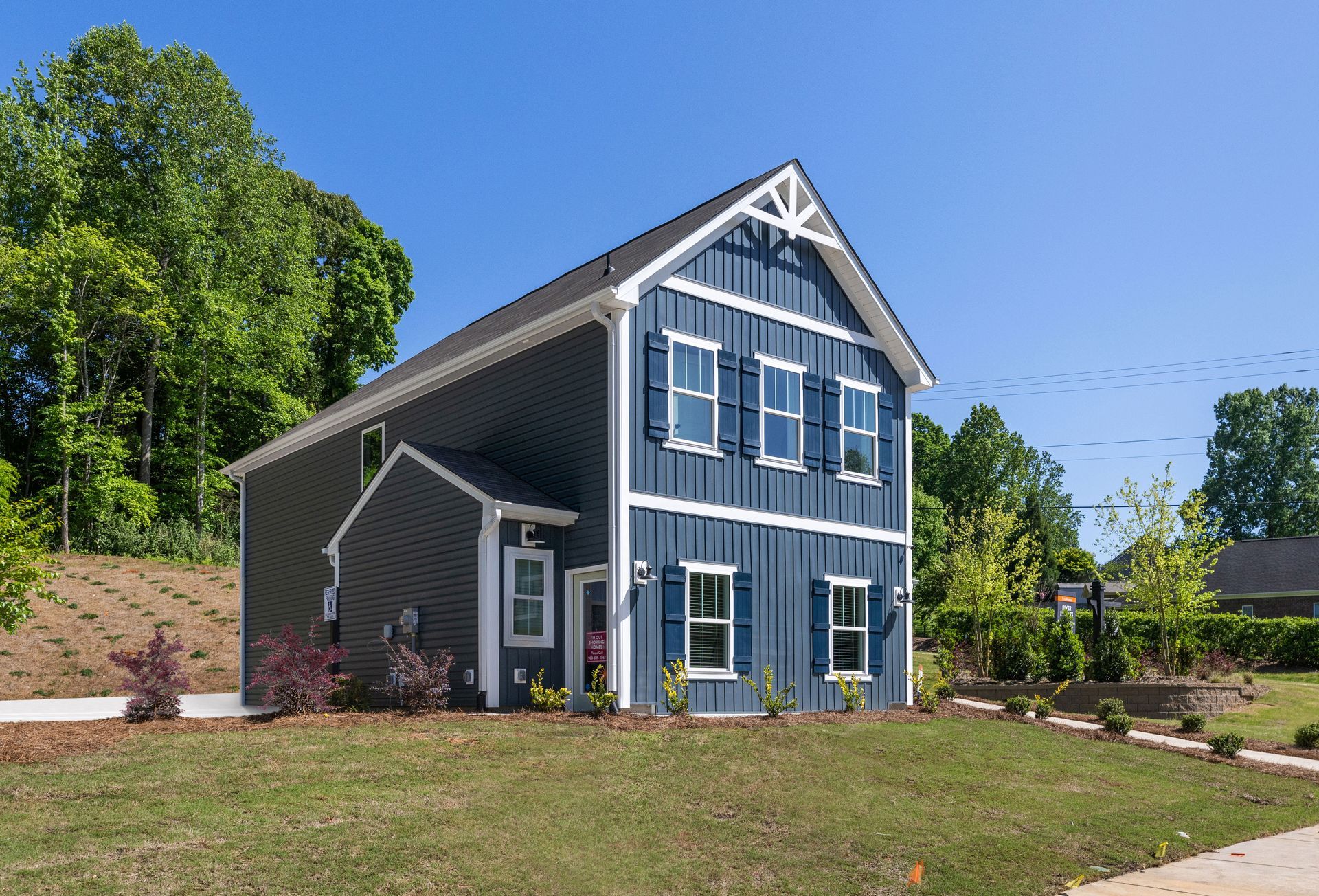 A blue house with white shutters is sitting on top of a lush green hillside.