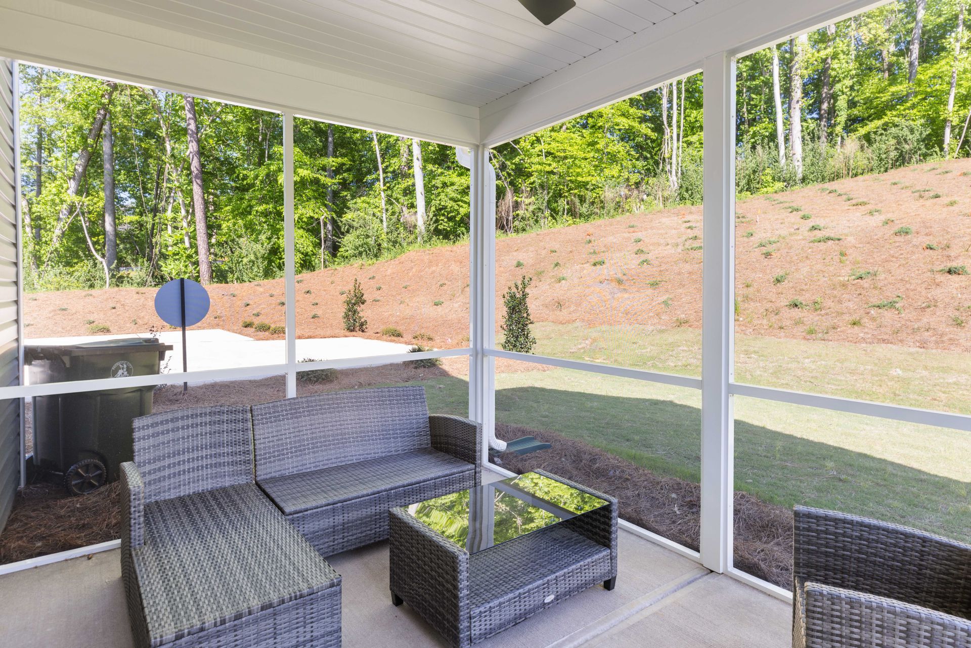 A small house with a porch and trees in the background.