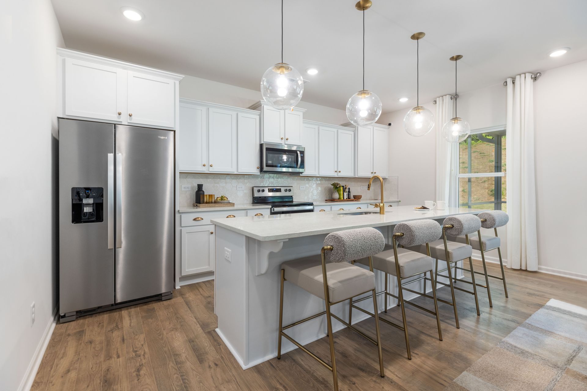A kitchen with white cabinets , stainless steel appliances , and a large island.