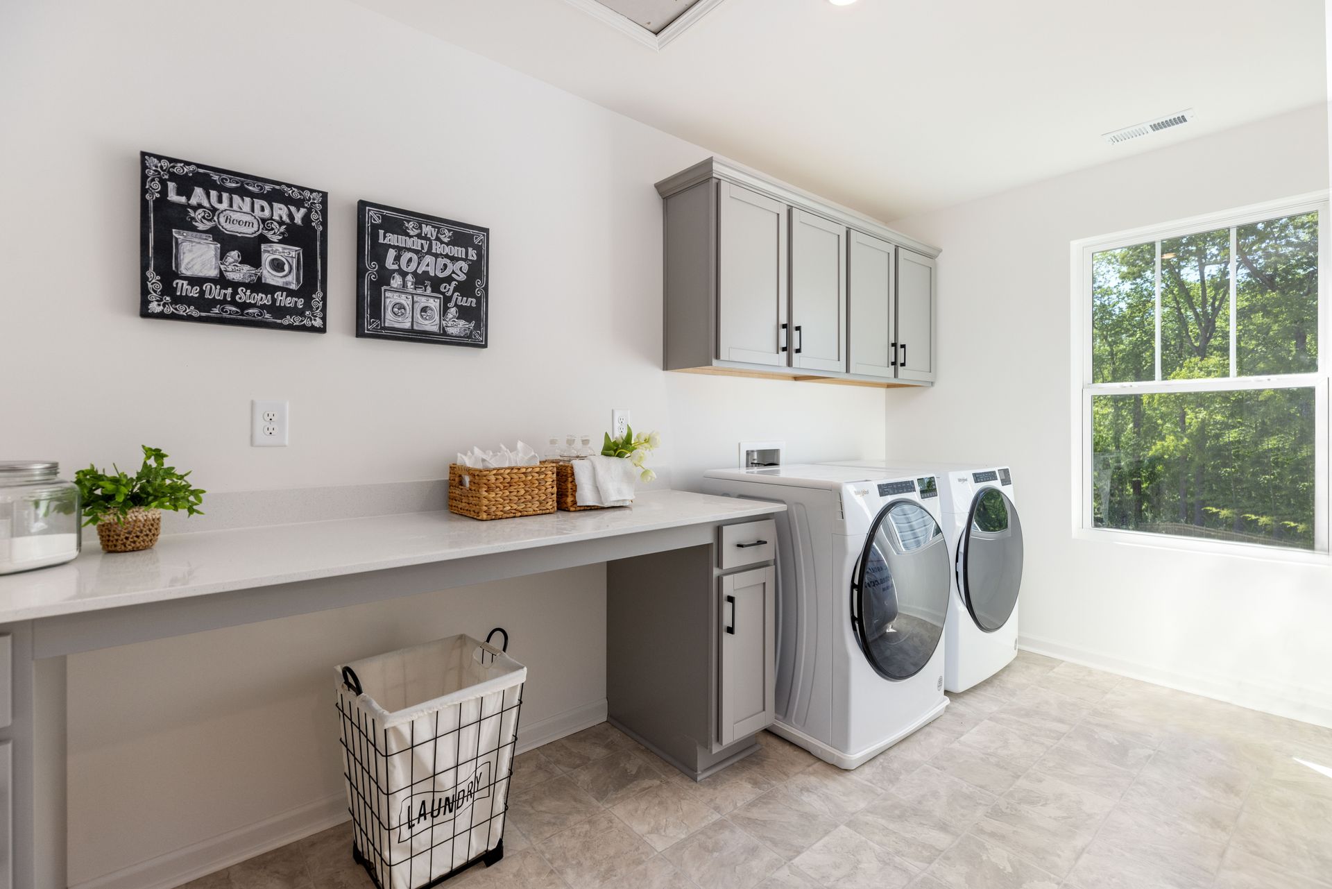 A laundry room with a washer and dryer , a desk , and a window.