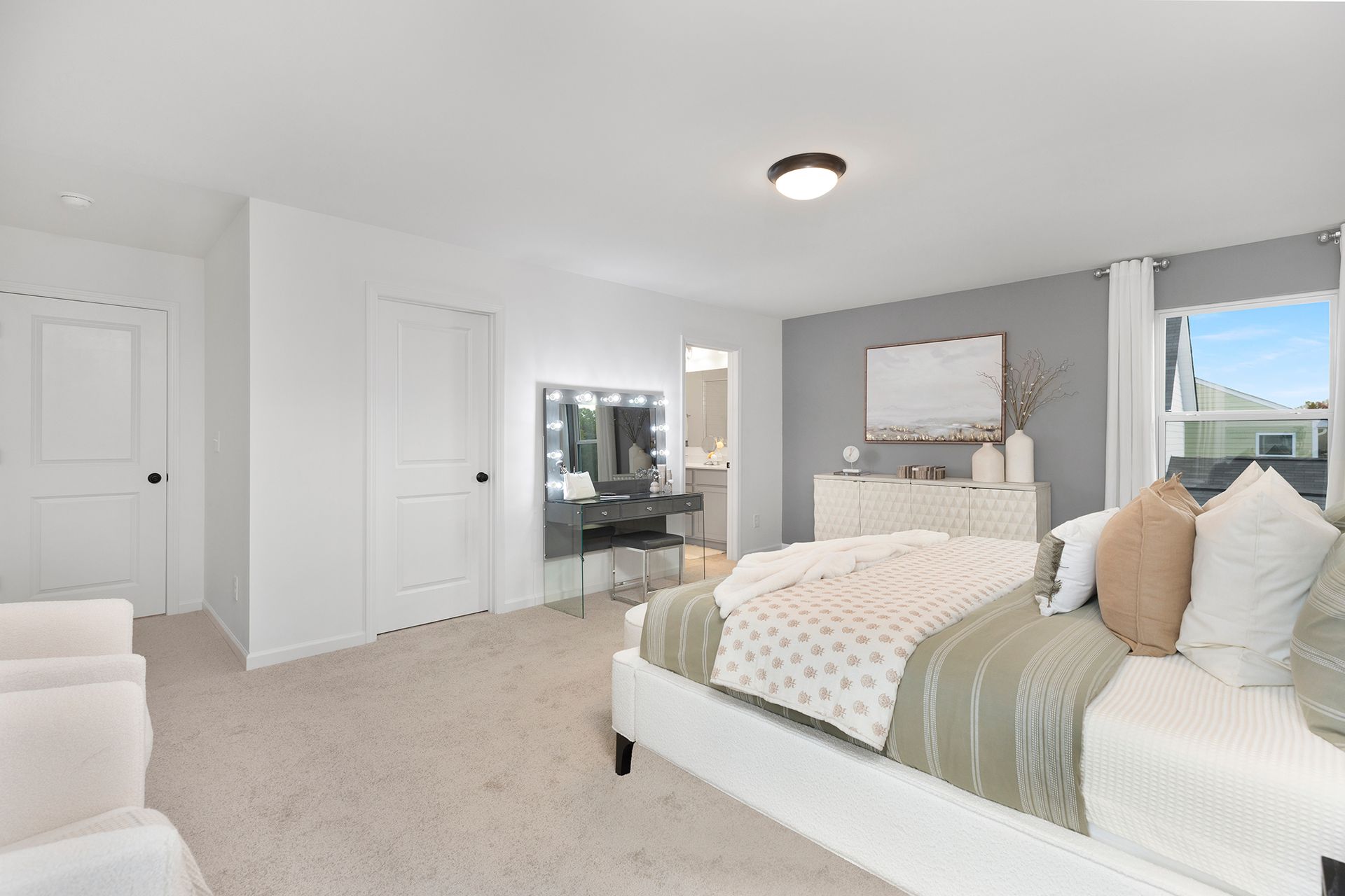 A bedroom with a large bed and a vanity.