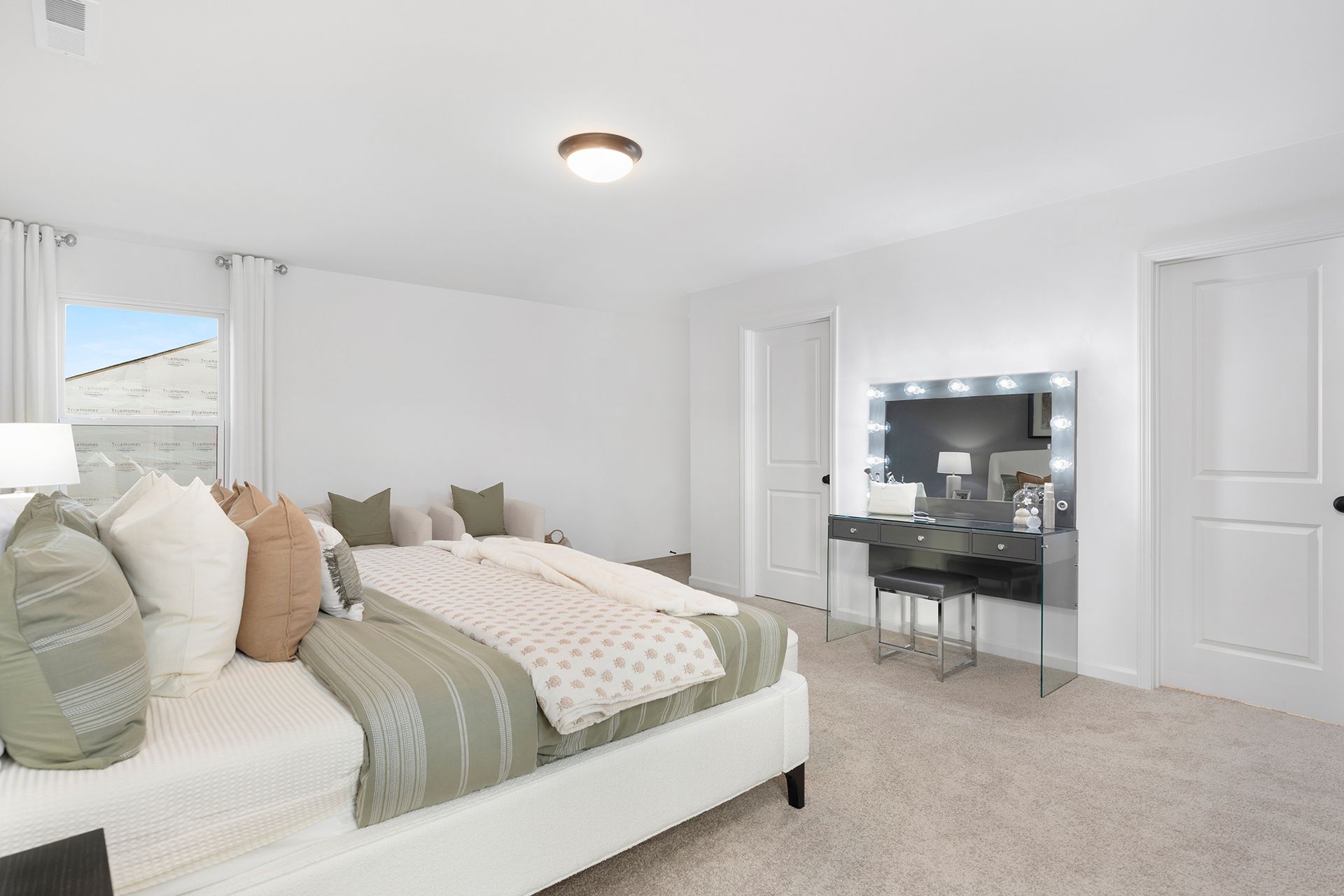 A bedroom with a large bed and a vanity.