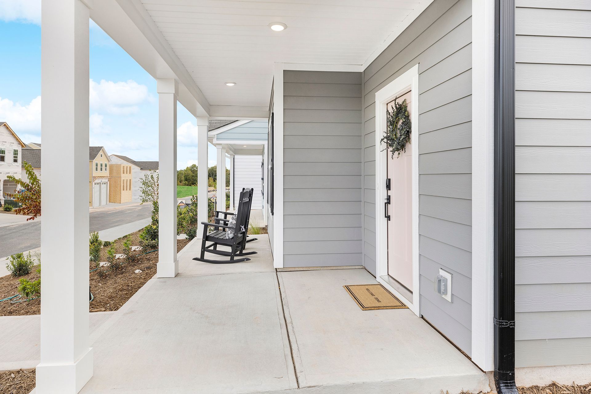 A porch with rocking chairs and a wreath on the door of a house.