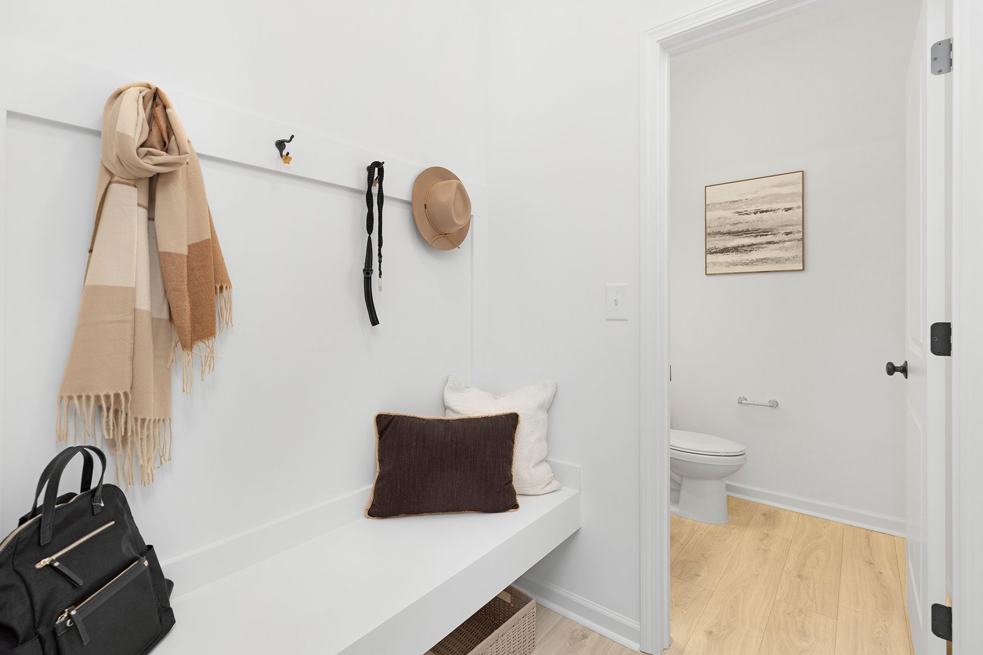 There is a bench in the hallway with a hat hanging on the wall.
