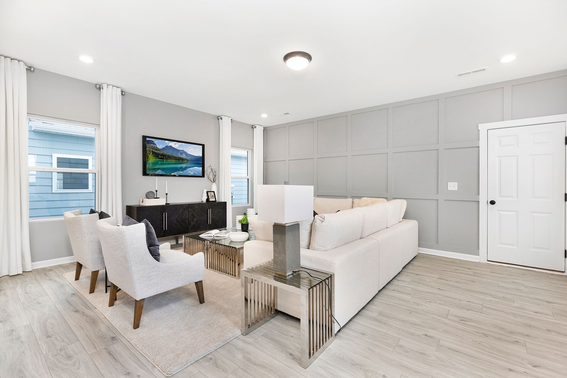 A living room with a couch , chairs , and a television on the wall.