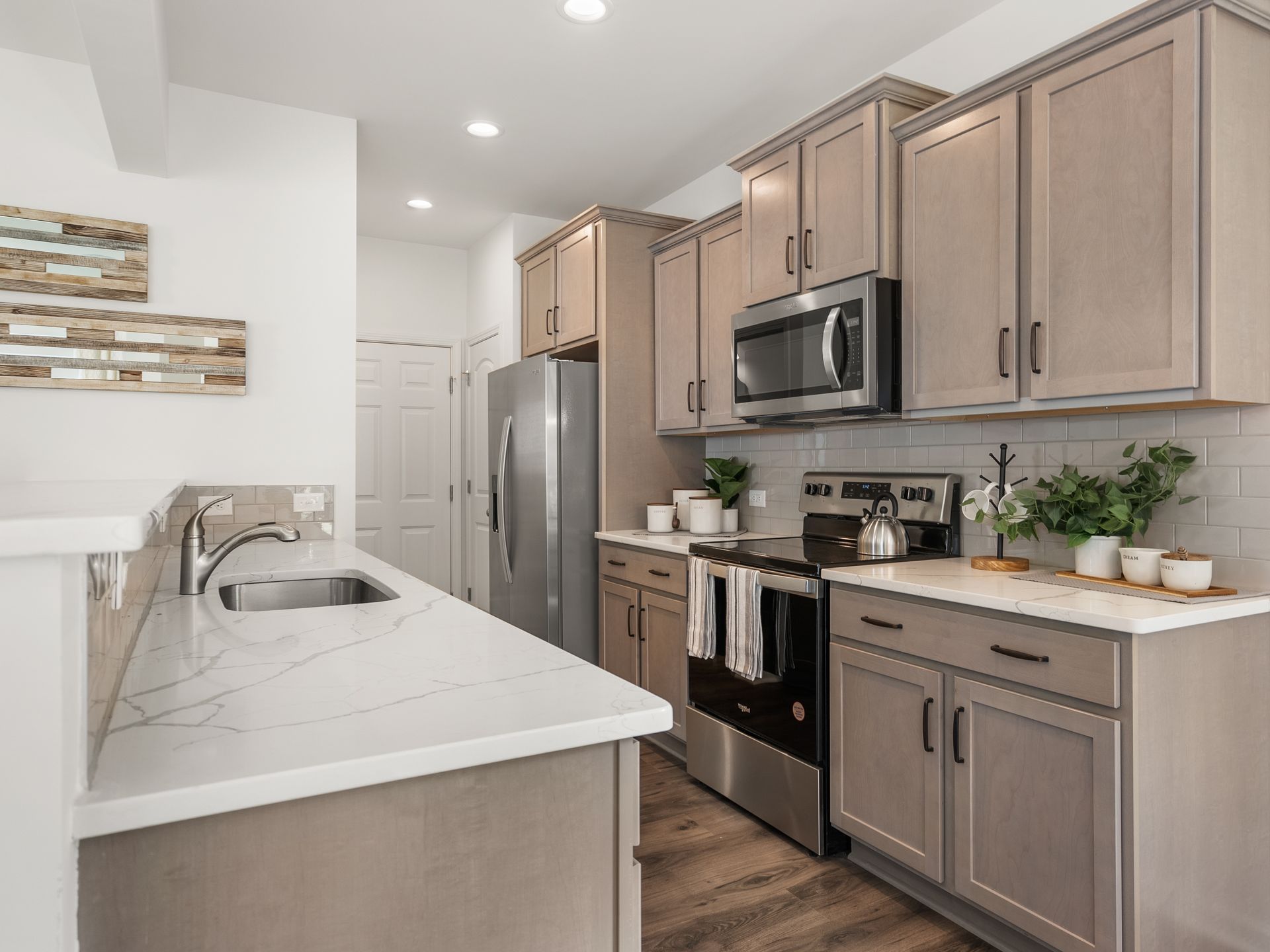 A kitchen with stainless steel appliances and gray cabinets.