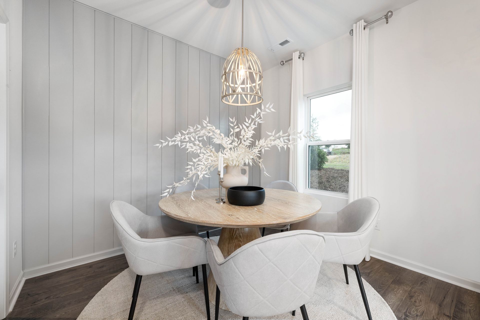 A dining room with a round table and white chairs.