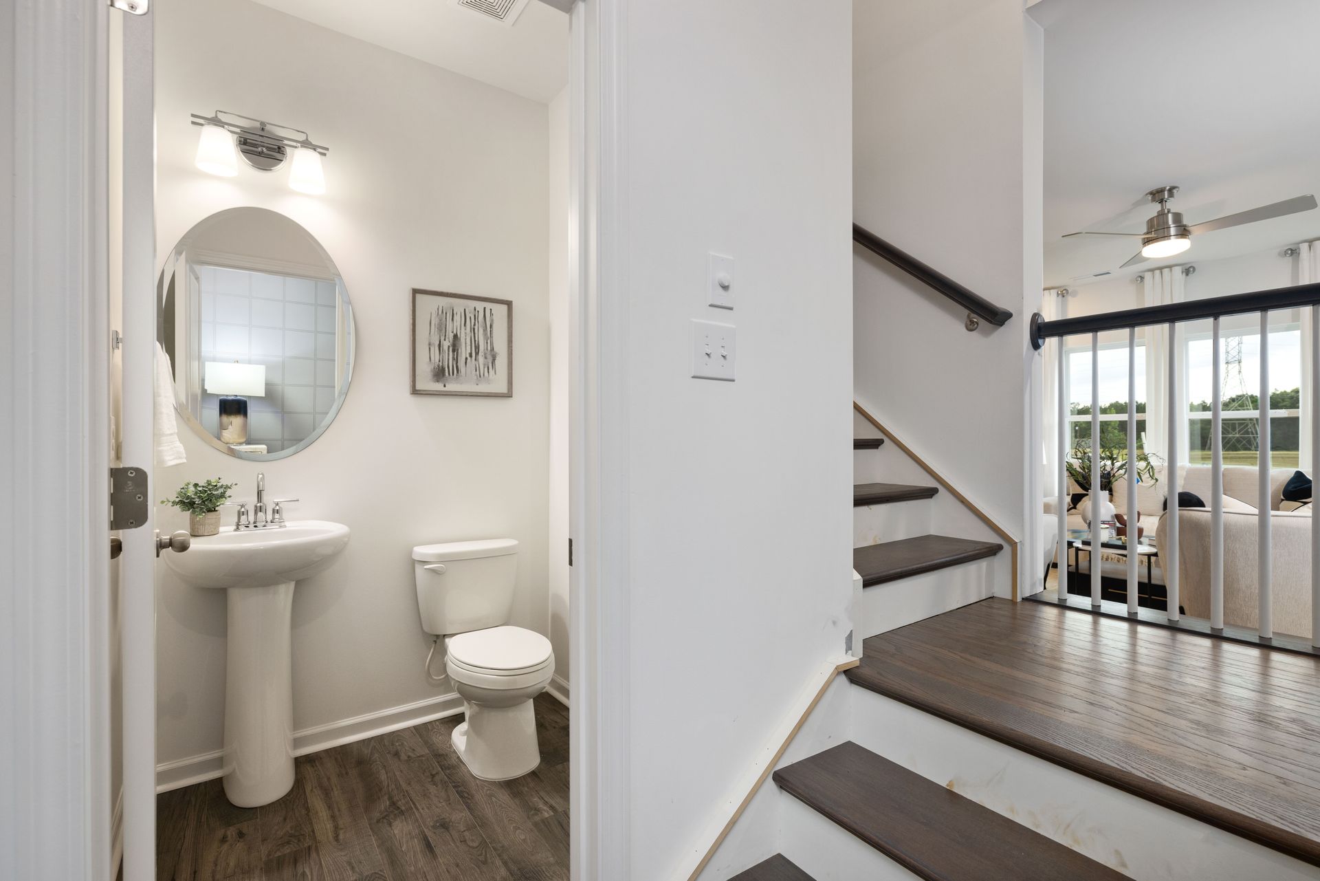 A bathroom with a sink , toilet , mirror and stairs.