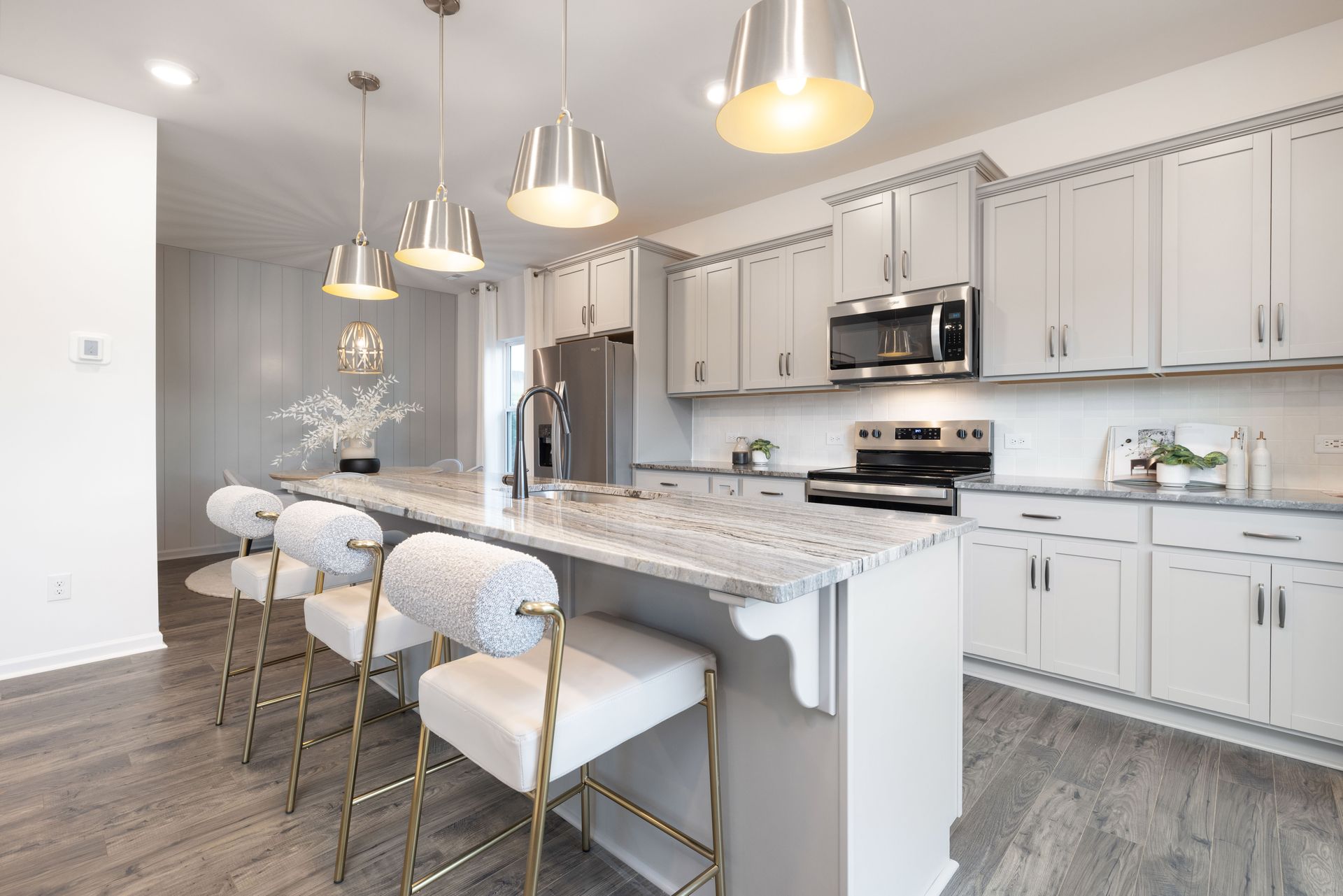 A kitchen with white cabinets , granite counter tops , stainless steel appliances , and a large island.