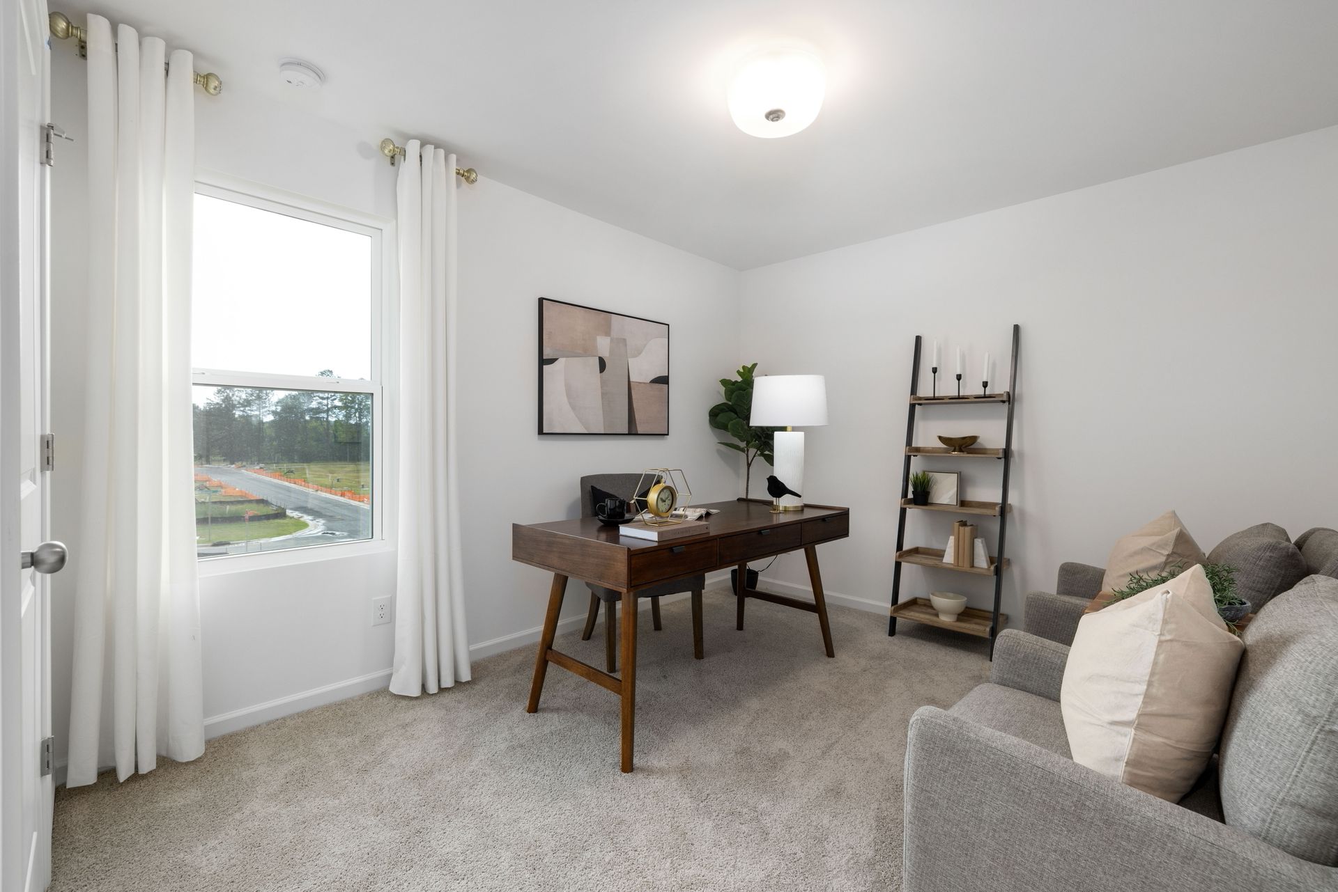 A living room with a desk , couch , and window.