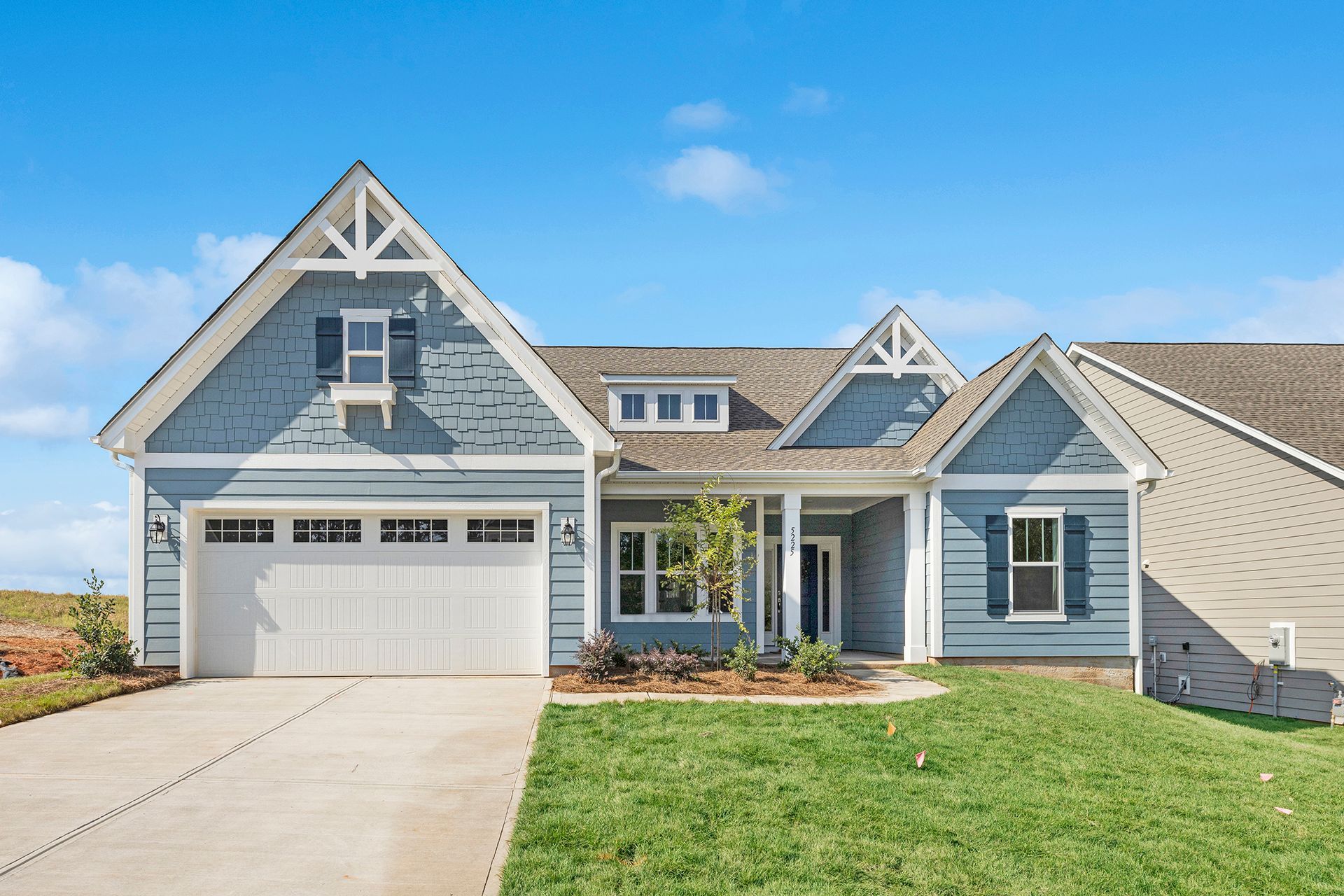 A large blue and white house with a large garage and a driveway.