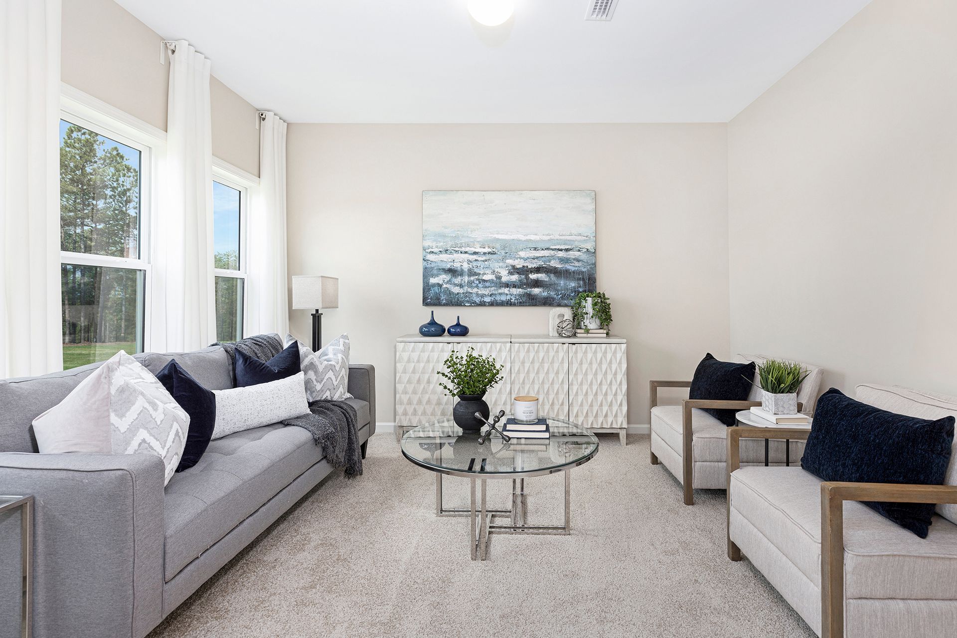 A living room with a couch , chairs , a coffee table and a painting on the wall.