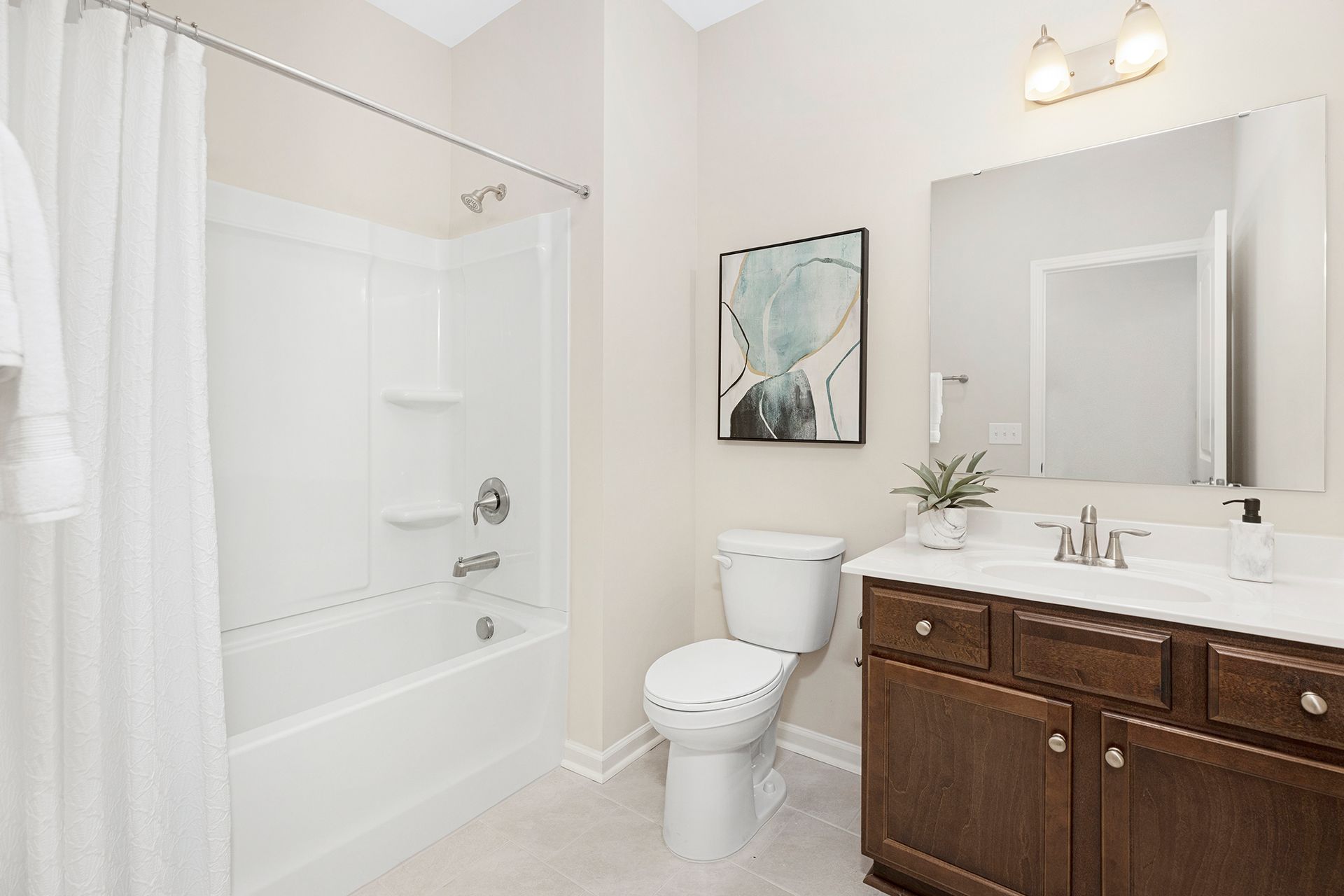 A bathroom with a toilet , sink , tub and mirror.